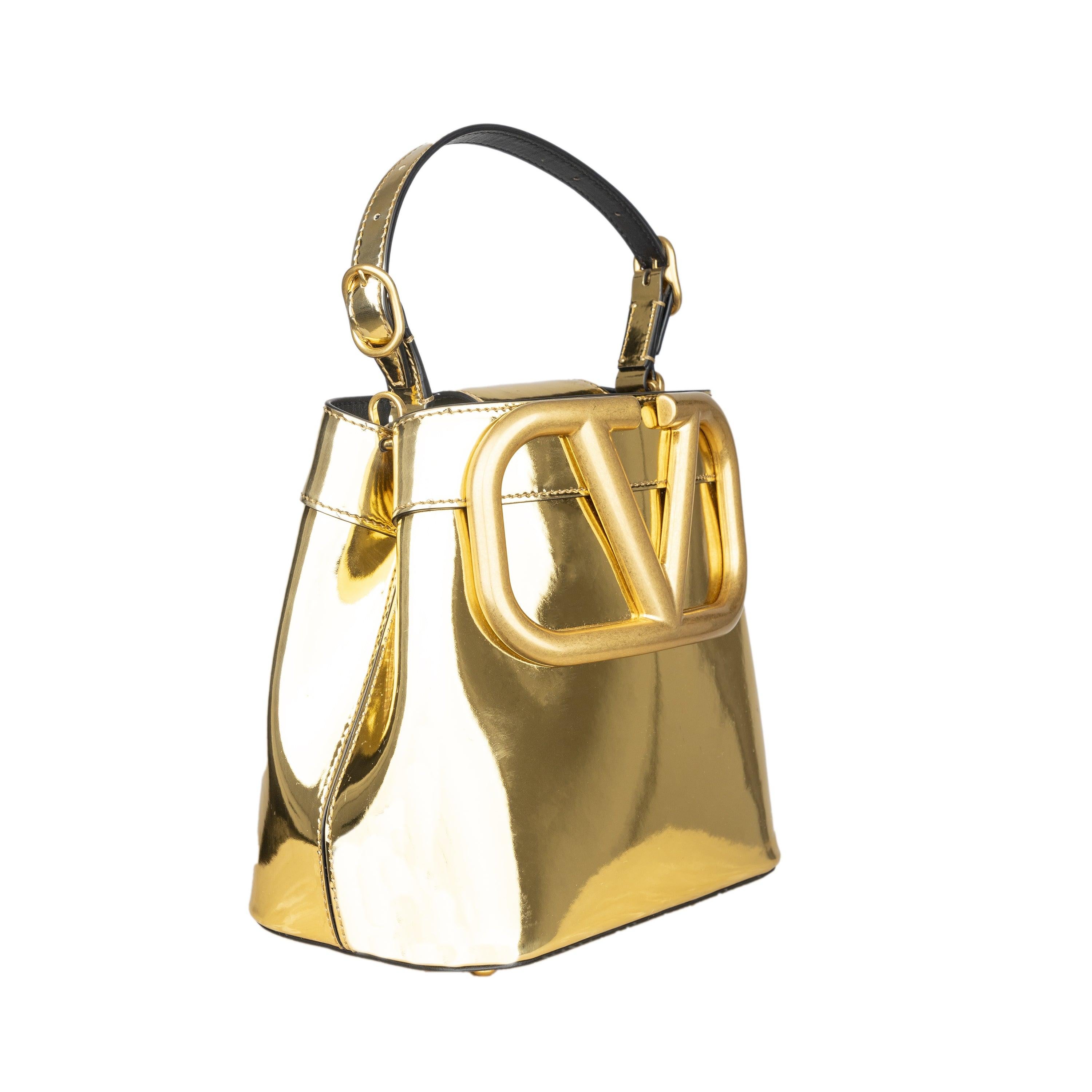 The Valentino Supervee Logo Tote Bag is a stunning accessory crafted from high-quality leather and featuring a bold metallic effect. The front logo adds a touch of luxury, while the magnetic closure and inside pockets provide practicality. With an
