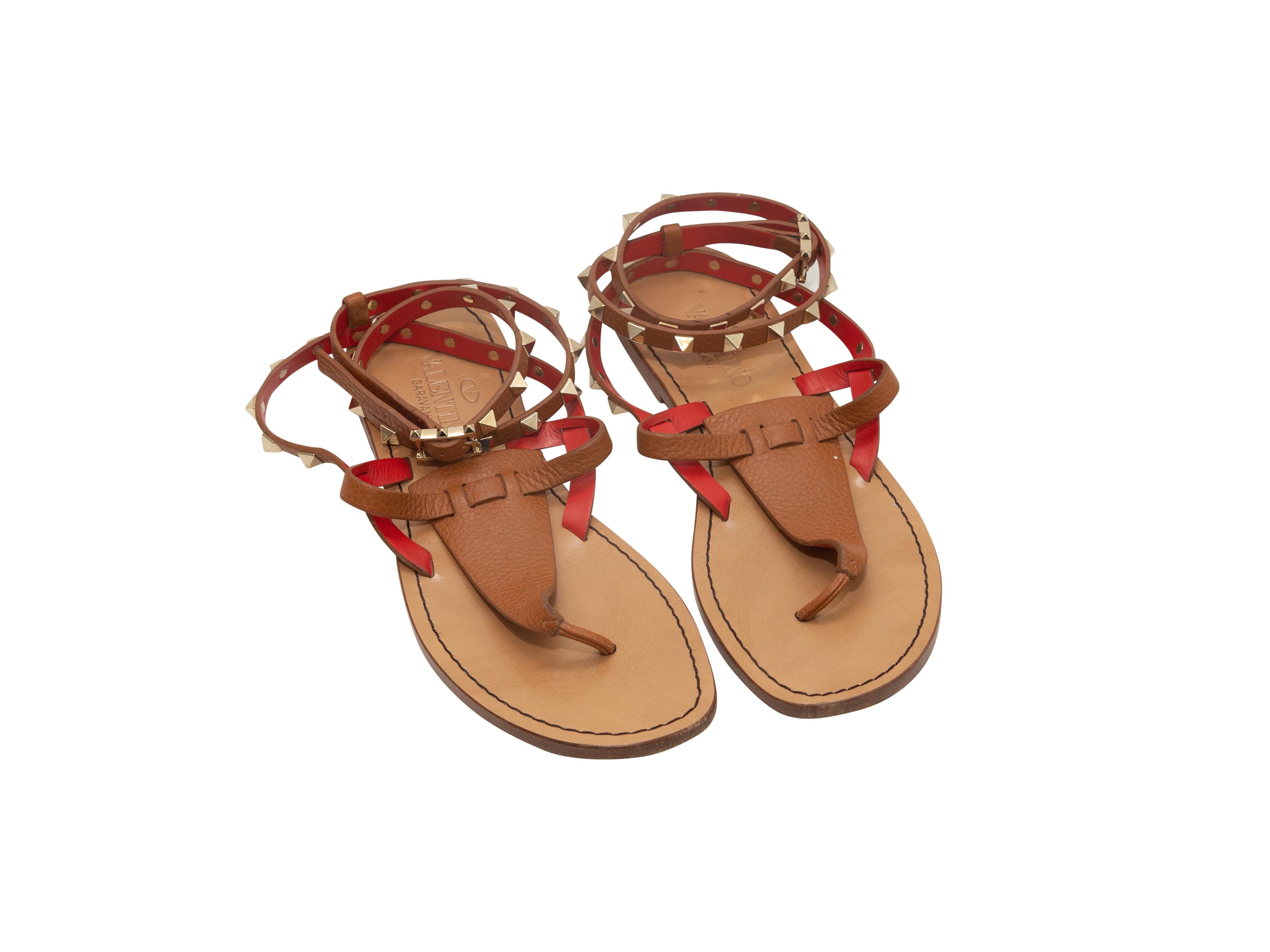 Product details: Tan and red leather strappy thong sandals by Valentino. Rockstud detailing throughout. Buckle closures at ankle straps. Designer size 38. 
Condition: Pre-owned. Good. Wear at soles and leather. Heavy wear at toe straps.