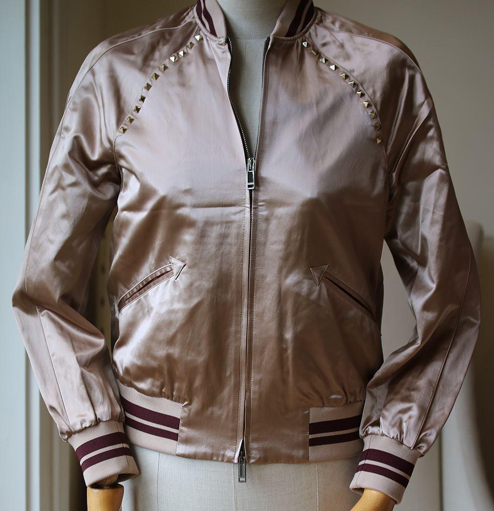 Valentino's bomber jacket is cut from lustrous satin. This glossy design is trimmed with the house's iconic 'Rockstuds' along the sleeves and finished with sporty striped ribbed-knit trims. Blush satin. Two-way zip fastening through front. 62%