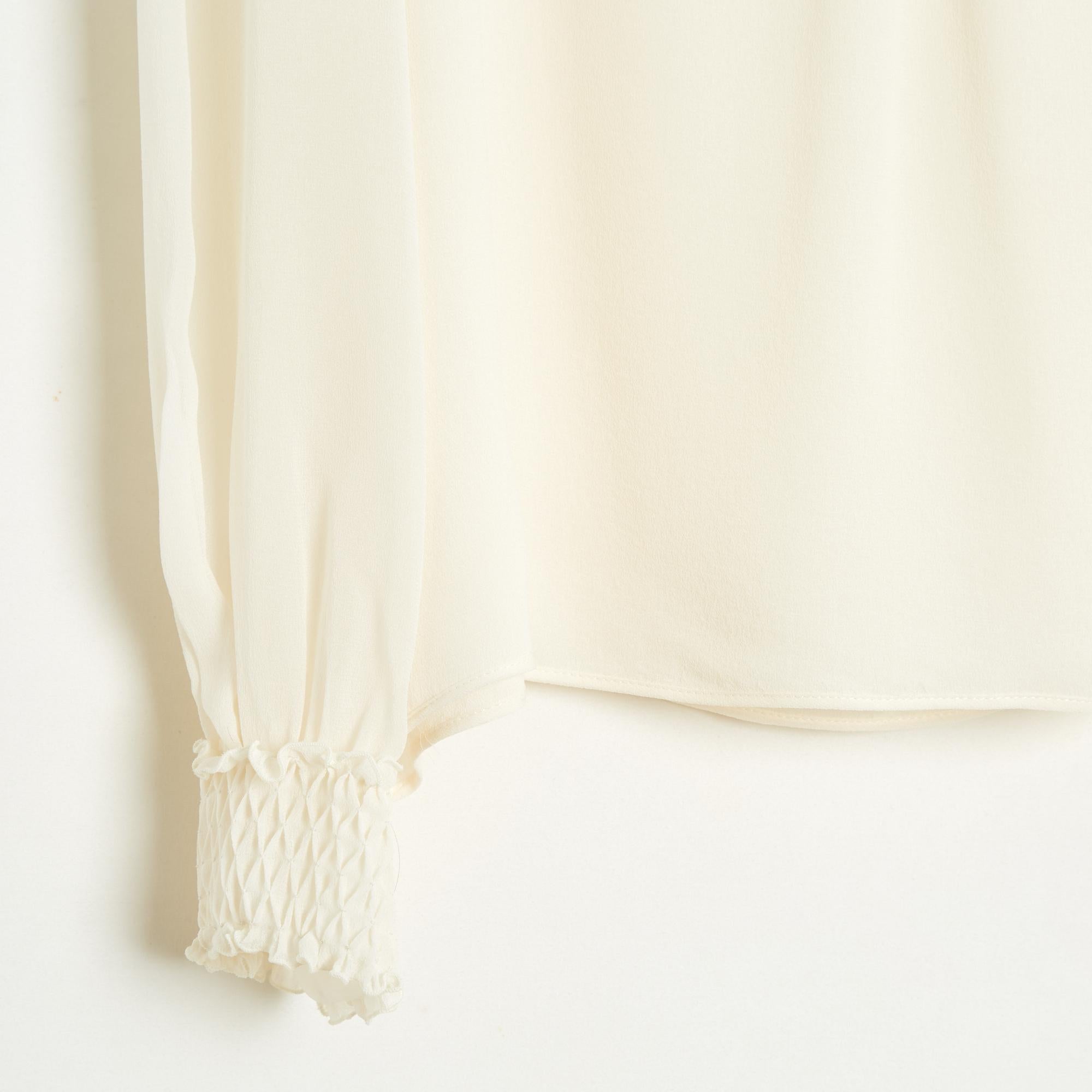 Top Valentino blouse in ecru silk crepe, straight cut, high smock collar, like the cuffs of the long sleeves, closed by 4 mother-of-pearl buttons behind the neck, lining of the same fabric on the front and back. Unfortunately no more composition or
