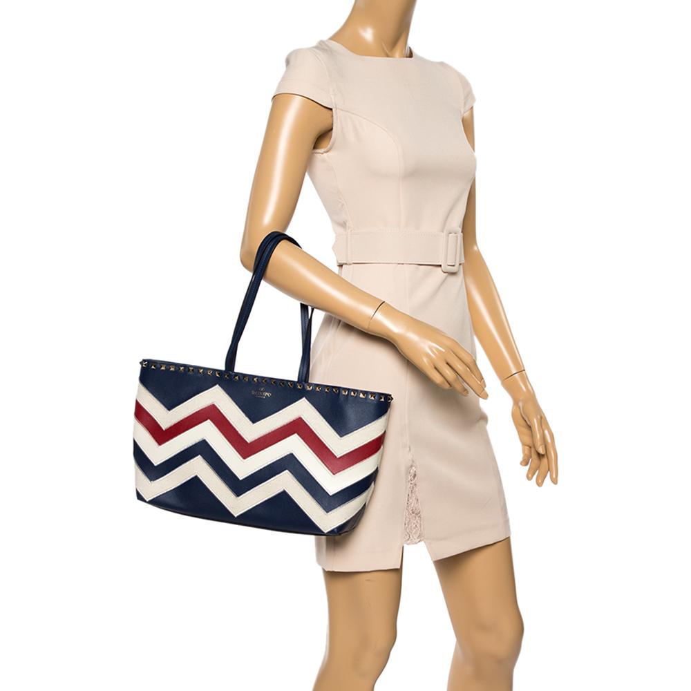 The shopper tote to buy today is this one by Valentino! Crafted with expertise, the tote has chevron patterns achieved using leather and canvas, two leather handles, a spacious interior, and signature studs lined along the top edge of the