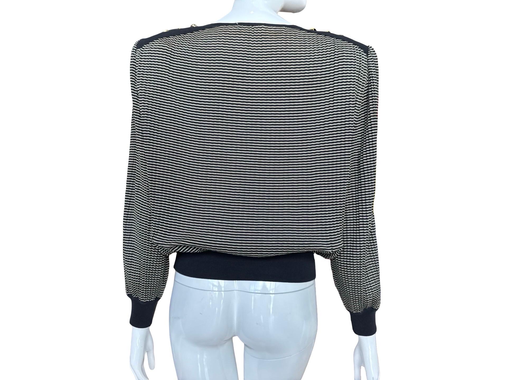 Tricot de coton léger des années 90 de Valentino qui est tout sauf simple.  Il est réalisé dans un tissu fin plissé en accordéon à rayures noires et blanches, avec des épaules noires contrastées, des boutons et des épaulettes dorés de style