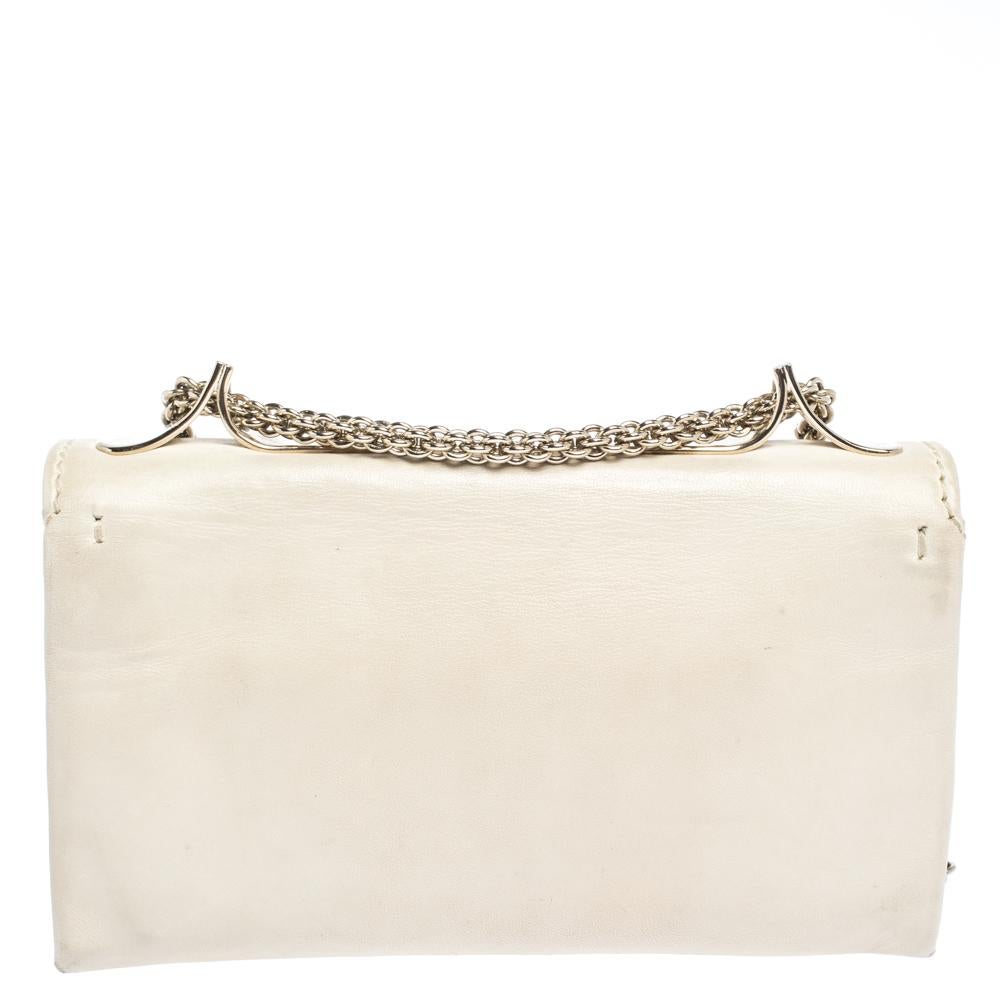 This Va Va Voom clutch bag from Valentino has a pretty captivating design. Crafted from Vanilla-hued leather, the bag features a flap, a canvas-lined interior, and a long shoulder chain. It also comes with a hand slot that is decorated with their