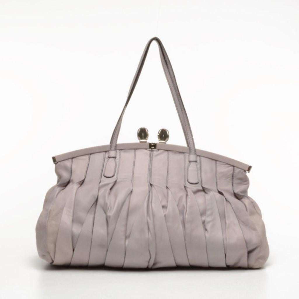 This lovely and sophisticated handbag is the perfect for any Valentino girl out there. Made from lavender colored leather, the exterior features a soft pleating design and a snap top closure. The carry all interior is lined with silver tone satin