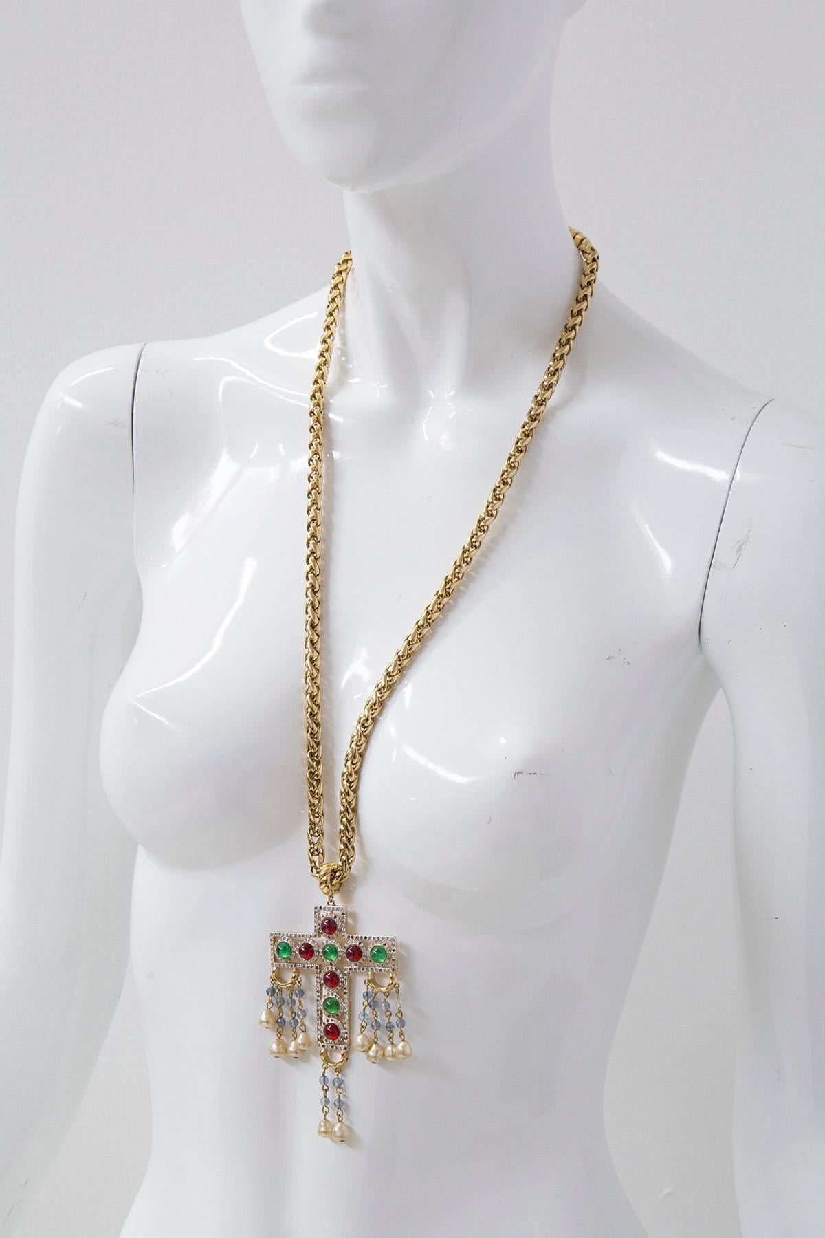 Eccentric chain necklace with Valentino cross branded on the back. The chain has an intricate inlaid design with a clip fastening made of gold-plated metal.
The Chain features a pendant cross element, decorated with ruby and emerald effect