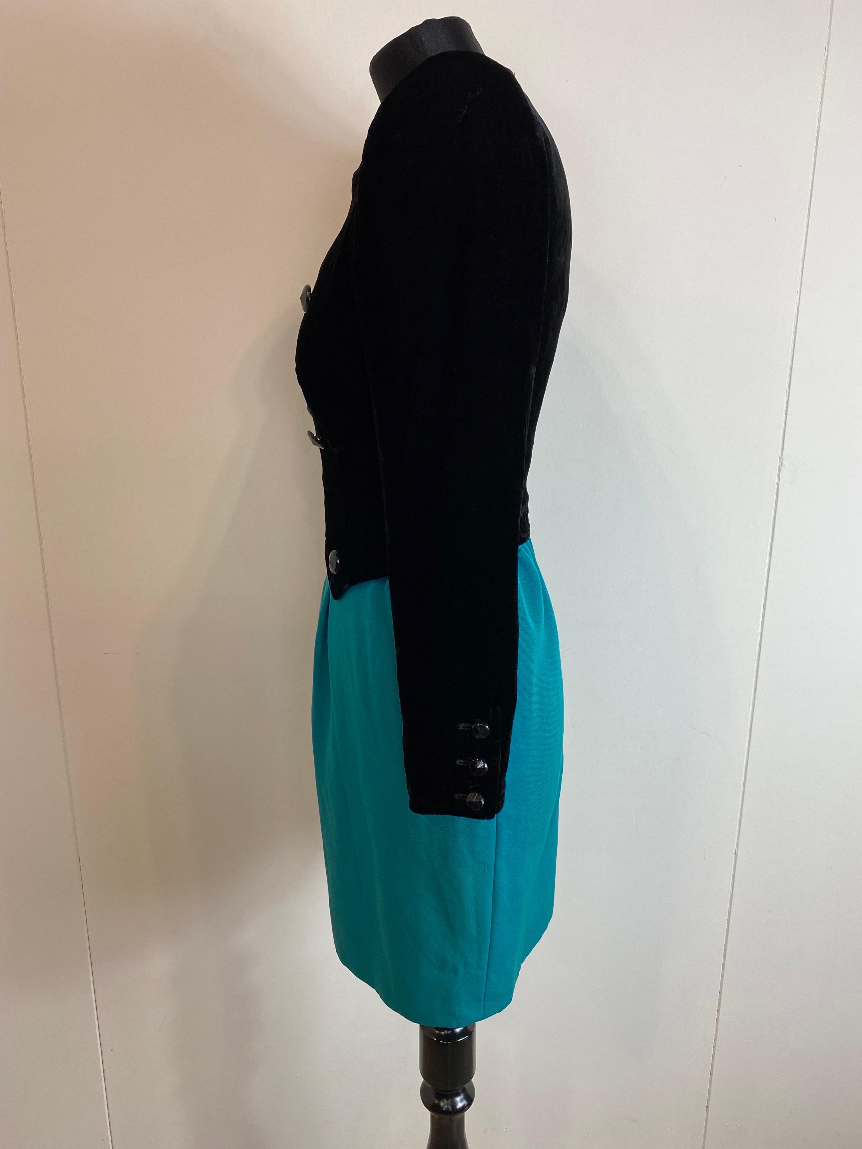 Abito vintage in nero e verde di Valentino. 
La parte superiore è in velluto, la gonna in lana. 
Scollo quadrato e bottoni decorativi. 
Con spallacci.
Chiusura con zip al centro della schiena. 
Presenta alcuni segni di usura come mostrato nelle
