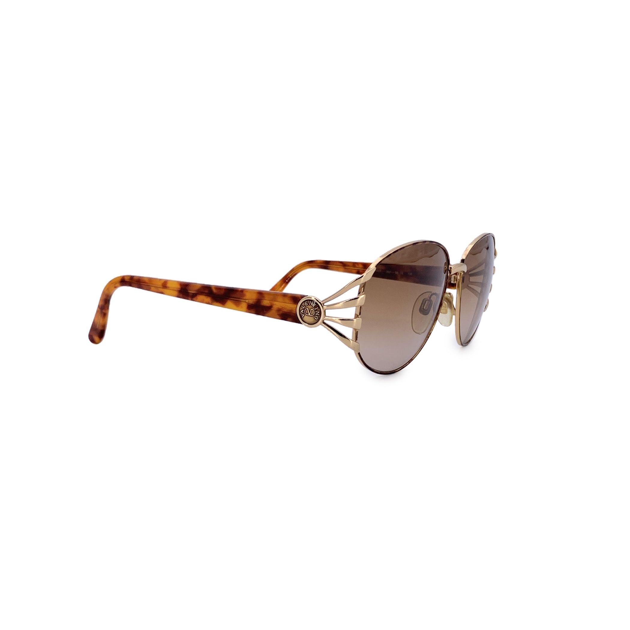 Zeitlos elegant mit einem Hauch von Bohème-Charme ist diese ovale Valentino Vintage-Sonnenbrille,m Mod. V431 zelebrieren einen raffinierten, von den 1980er Jahren inspirierten Stil. Der zarte goldene Metallrahmen strahlt dezenten Luxus aus, während