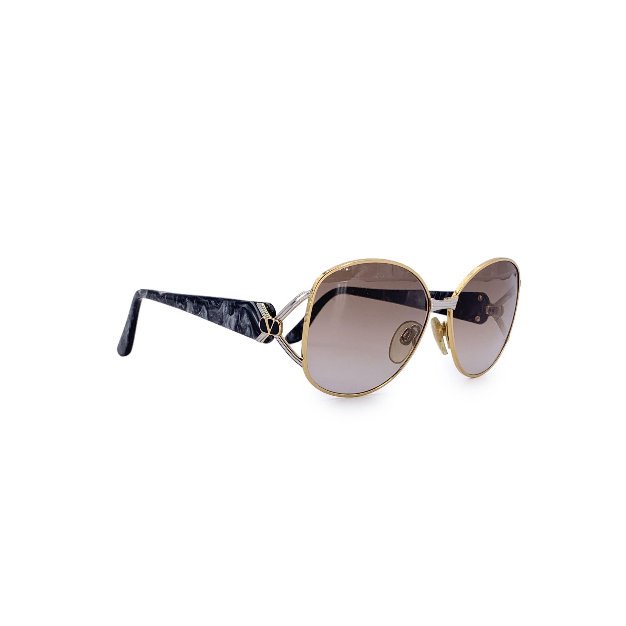 Zeitlos elegant mit einem Hauch von Bohème-Charme ist diese ovale Valentino Vintage-Sonnenbrille, Mod. V350 zelebrieren einen raffinierten, von den 1980er Jahren inspirierten Stil. Die zarte goldene Metallfront strahlt dezenten Luxus aus, während