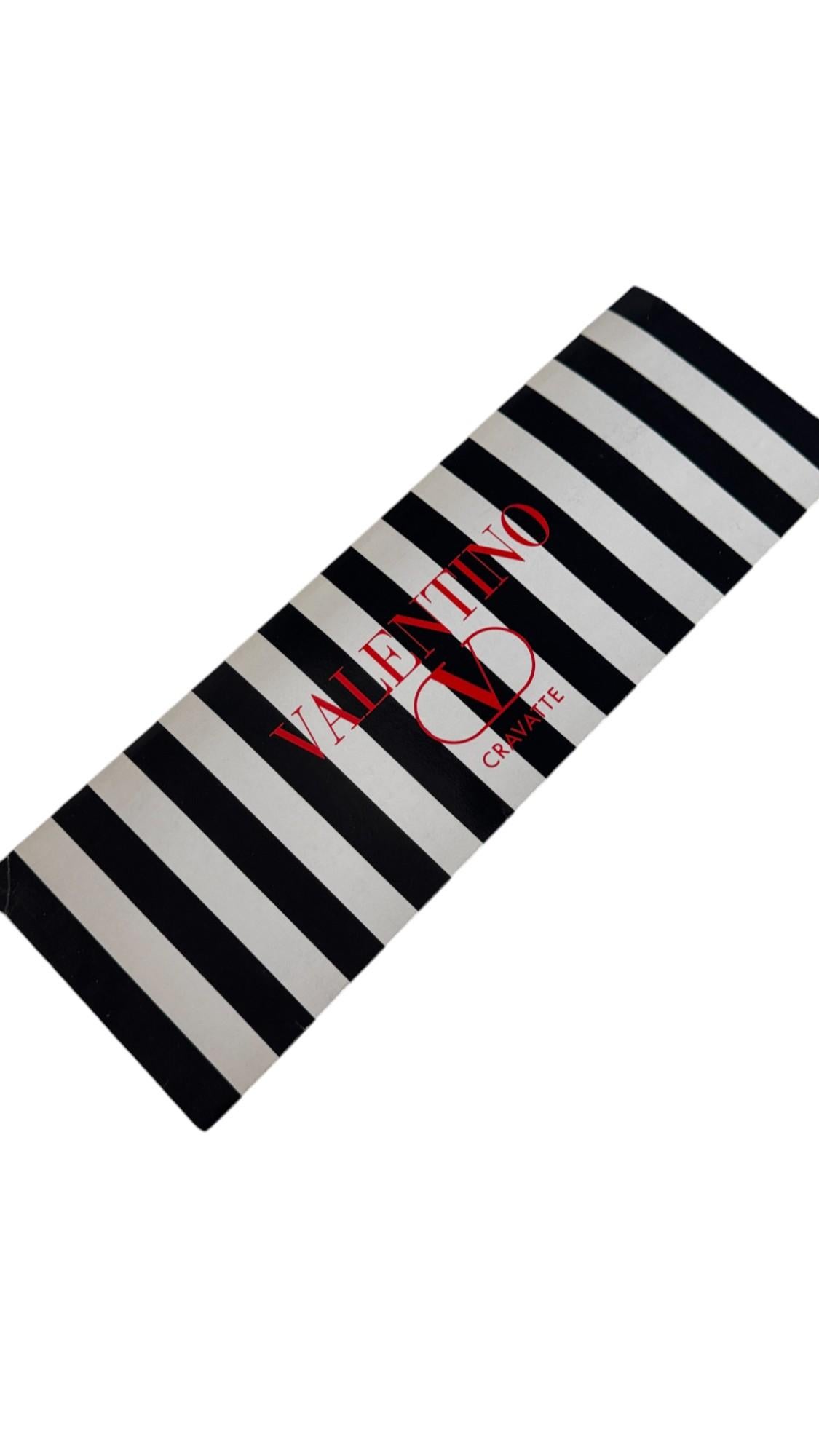 This refined vintage Valentino Cravatte tie showcases a sophisticated crosshatch geometric pattern in deep burgundy over a textured microdot grey silk background, creating a bold yet elegant visual effect that stands out while remaining impeccably