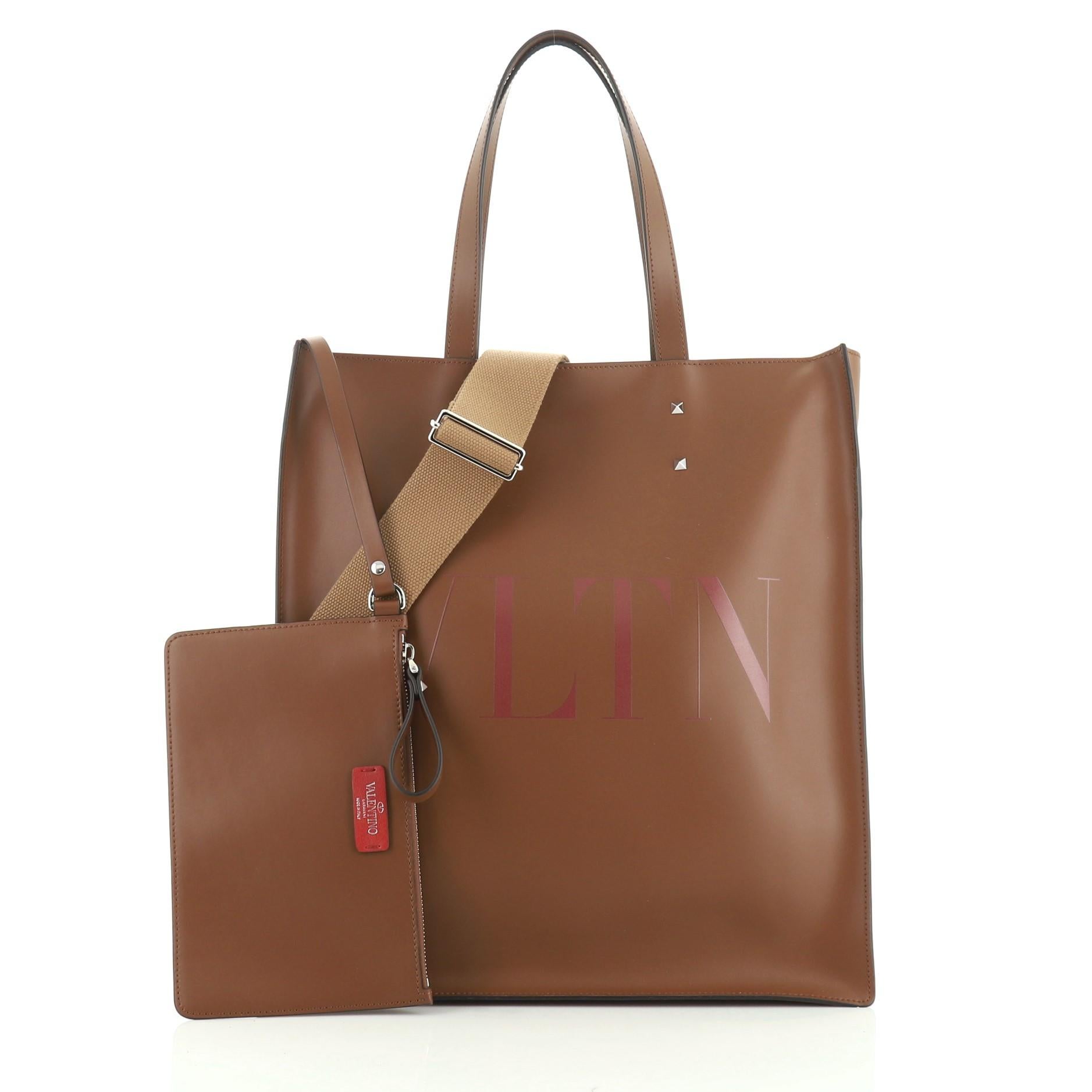 This Valentino VLTN Convertible Rockstud Tote Printed Leather Tall, crafted from brown leather, features dual flat handles and silver-tone hardware. It opens to a brown microfiber interior. 

Condition: Excellent. Slight creasing on exterior, small