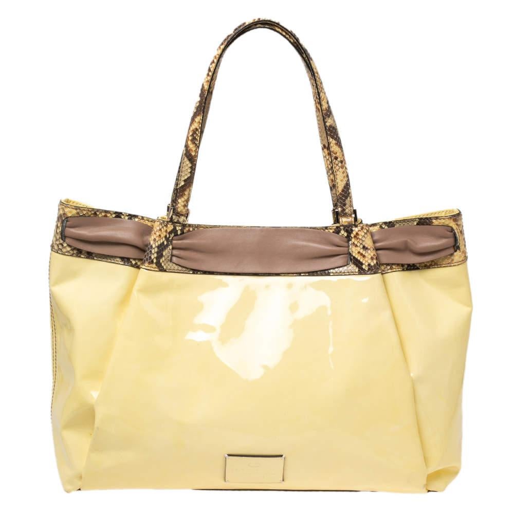 Elevate your everyday look by carrying this Valentino Aphrodite Bow bag. Crafted in patent leather, it has python trims, python handles, and bow detail at the front. It has a spacious fabric interior.

