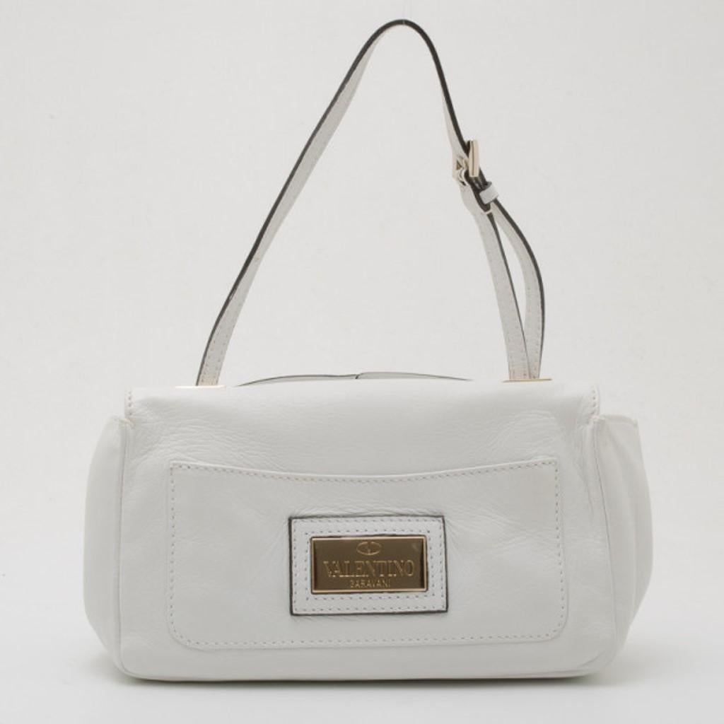 Decorated with a prominent white leather rosette on its big flap, this Valentino Shoulder Bag is sure to grab lots of compliments. This spacious bag holds an open patch pocket and an extra bold monogrammed pocket. It's fastened to an adjustable