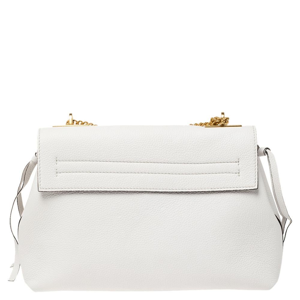 Crafted from leather, this white bag from Valentino impresses with its design and style. It flaunts the signature V logo with an attached ring accent on the front flap and opens to a spacious interior that can easily carry your daily essentials. The
