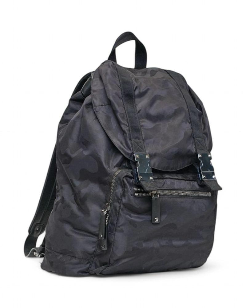 Valentino signature backpack, made of black nylon with camouflage pattern and iPrada Shopper bag, made of beige embossed leather with gold hardware. Equipped with a snap-on top closure, internally lined in tone-on-tone logo fabric with a convenient