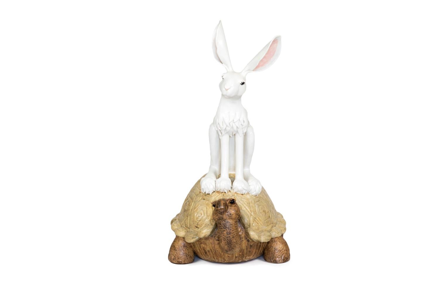 Valérie Courtet, signed.

Glazed stoneware sculpture figuring a rabbit sat on a tortoise back.
The rabbit is white, represented with hairs around its neck and on its paws, large ears pink on the interior, black eyes and slightly bending its head