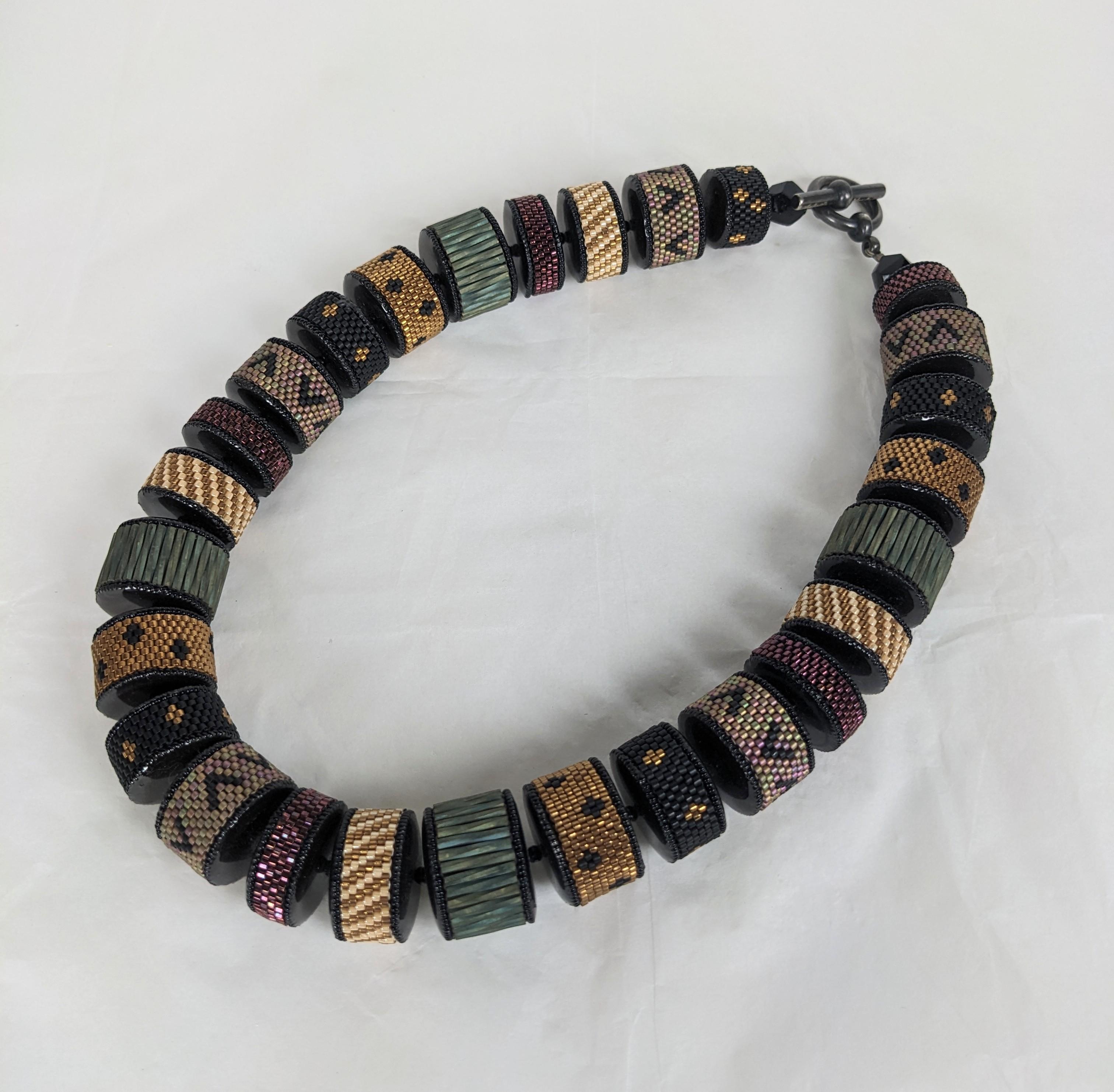Elaborate Valerie Hector Beaded Necklace from the 2000's. Artisanal beads, each individually hand woven into intricate patterns in Autumnal colors and then strung with jet spacers. Sterling toggle clasp, signed. 2000's USA. 20
