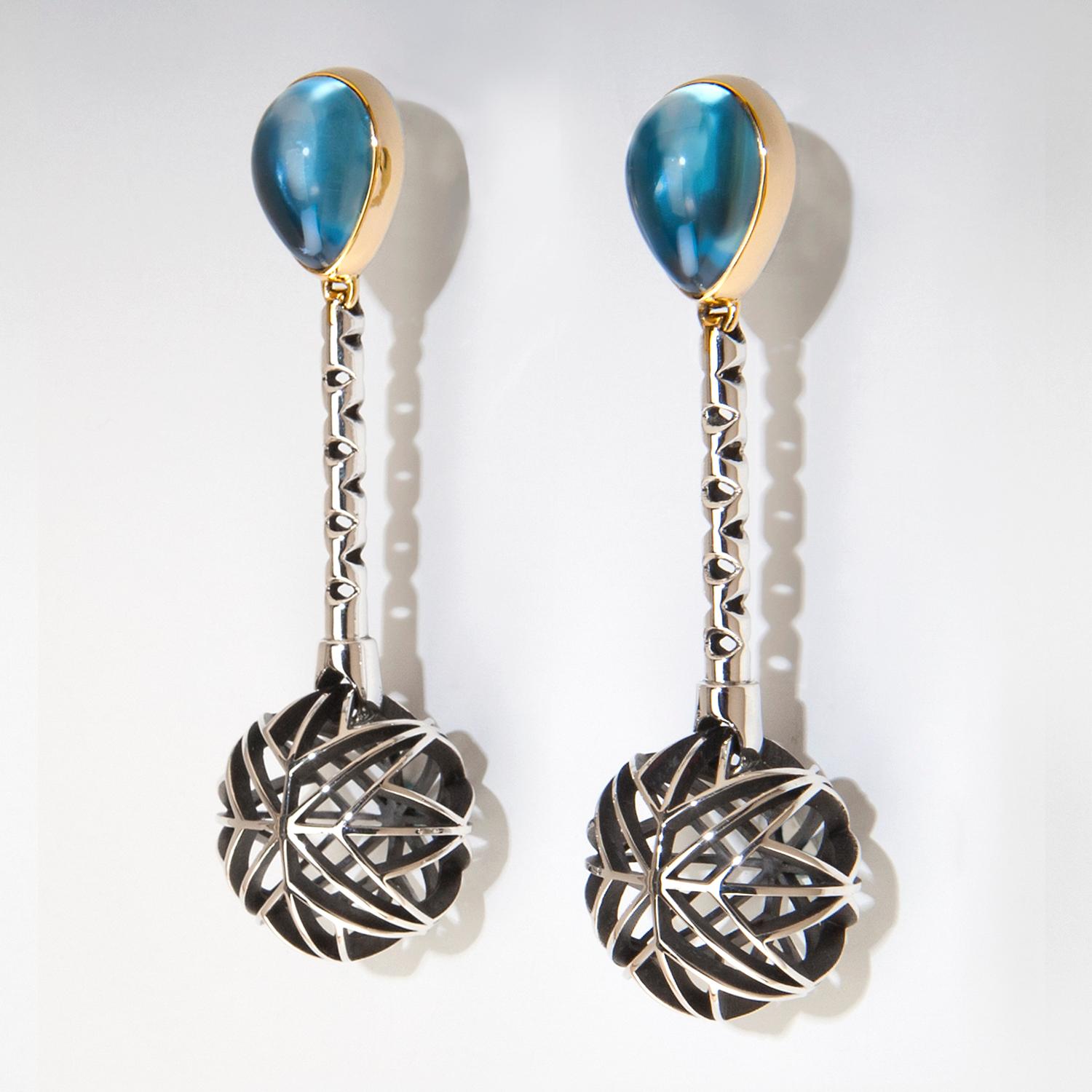 One of a Kind Earrings titled 'Shadows from a Blue Moon' are a variation of theme on Valerie Jo Coulson's Saul Bell Design Award winning Collection - 'Sunshine and Shadow'.  Custom cut Electric Blue Topaz cabochons are bezel set in 14k Yellow Gold