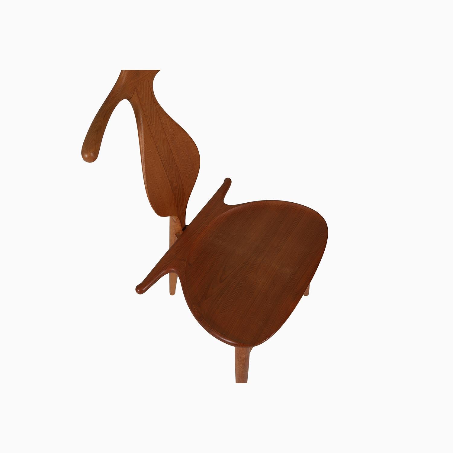 A sculptural masterpiece by Hans J Wegner, purportedly designed for the king of Denmark.  Chair back is a shirt hanger, the solid teak seat lifts to reveal storage for dressing items such as cuff links, watches, scarves etc.  This version has an oak