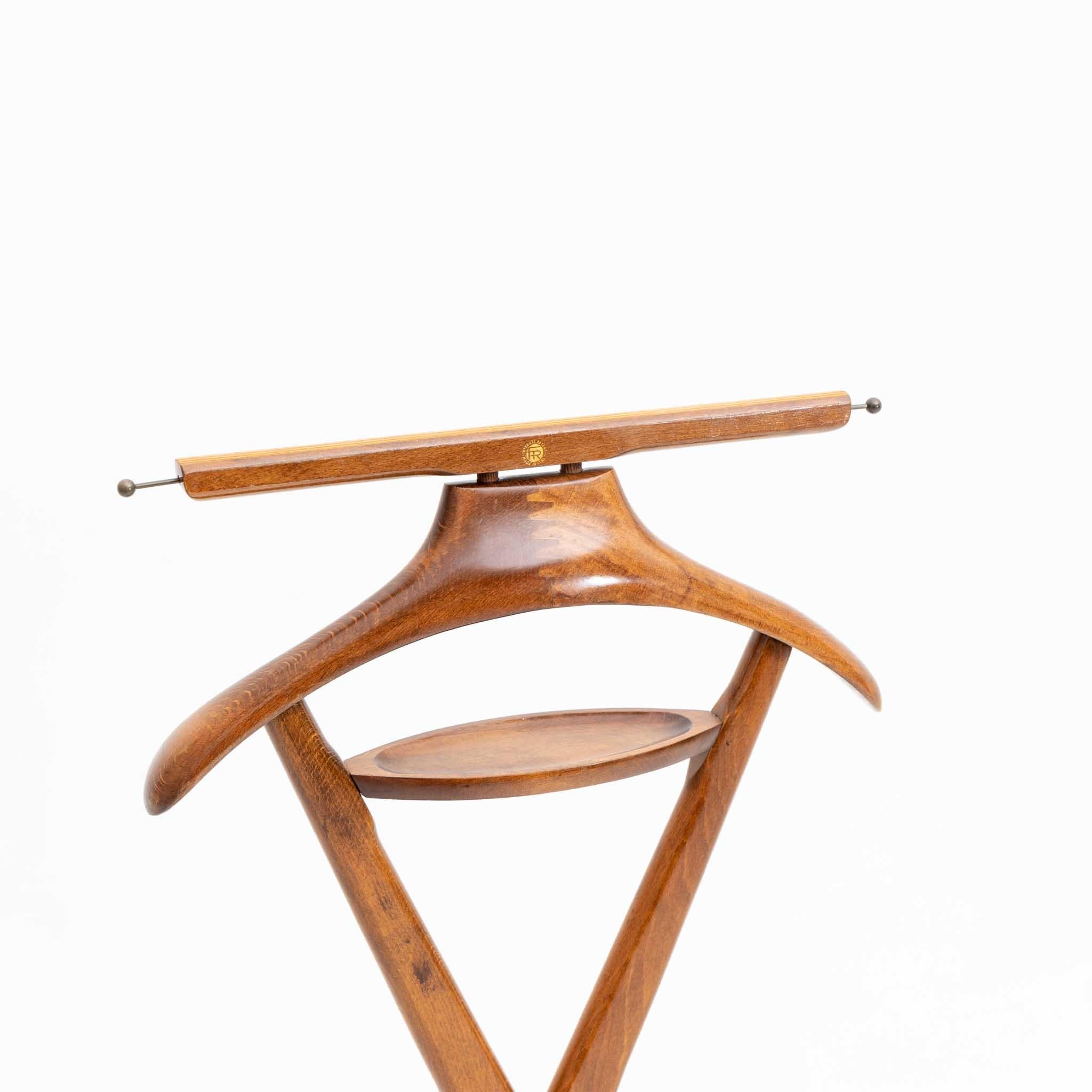Beech valet stand with x-shaped frame with one small shelf, a coat hook and trouser hanger. The clothes rack is equipped with wheels so it is easy to move. At the top stamp of the company Fratelli Reguiti.