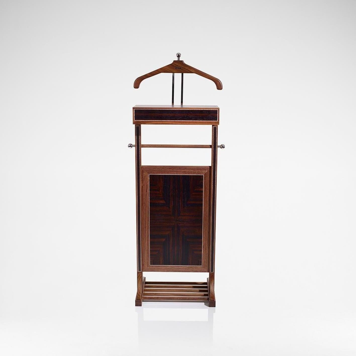 The Linley valet stand is a wonderfully practical piece of furniture that is used for hanging a suit and hat and holding small accessories. Handcrafted in walnut and Macassar with grey sycamore stringing and stainless steel detailing, the valet