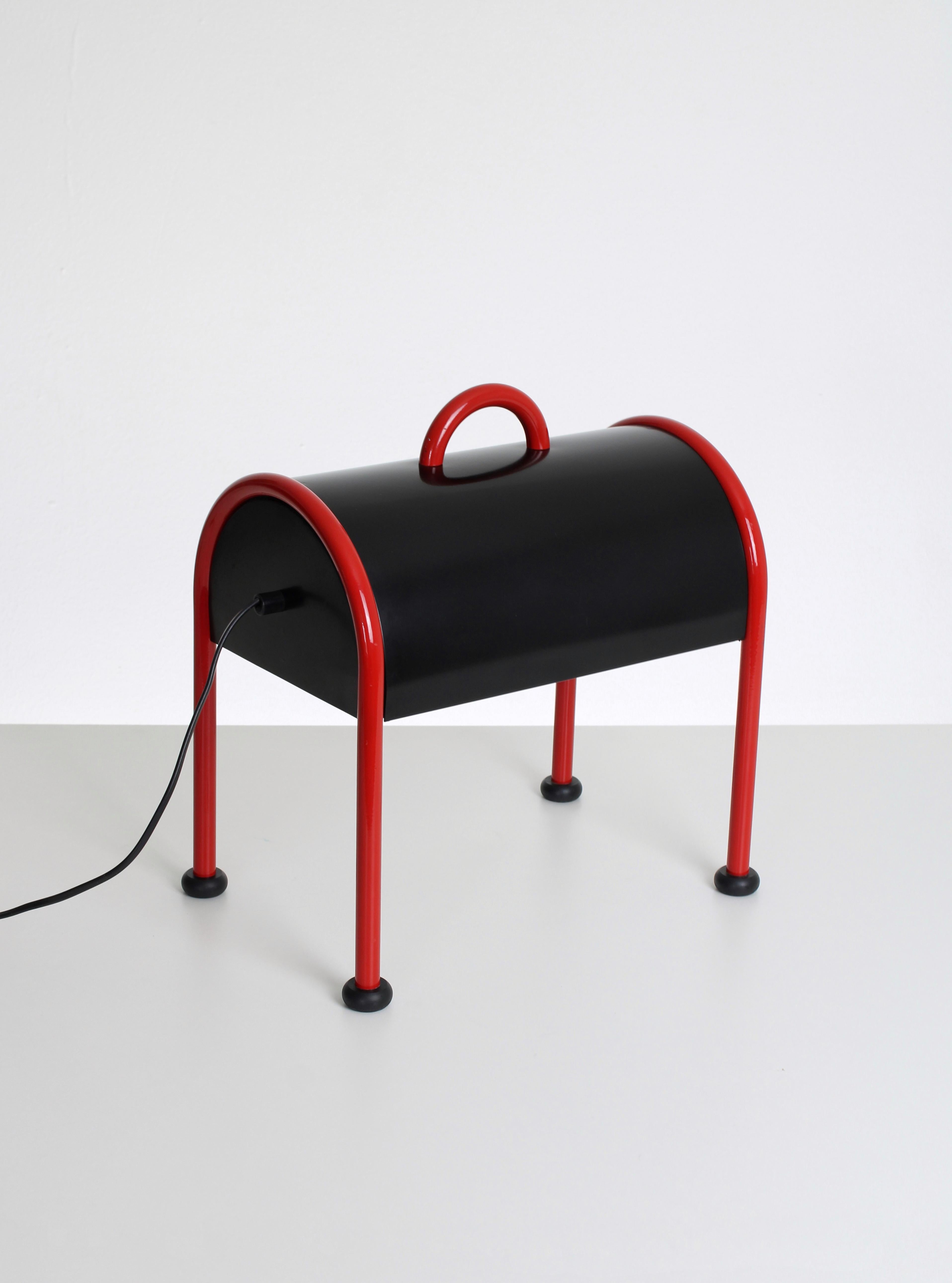 Vierbeinige Tischleuchte Modell Valigia. Diese seltsam geformte Tischleuchte ist einer der vielen Entwürfe von Ettore Sottsass. Inspiriert von der Idee einer einfachen Aktentasche. Die Tischleuchte Valigia ist eine Ikone des italienischen Designs,