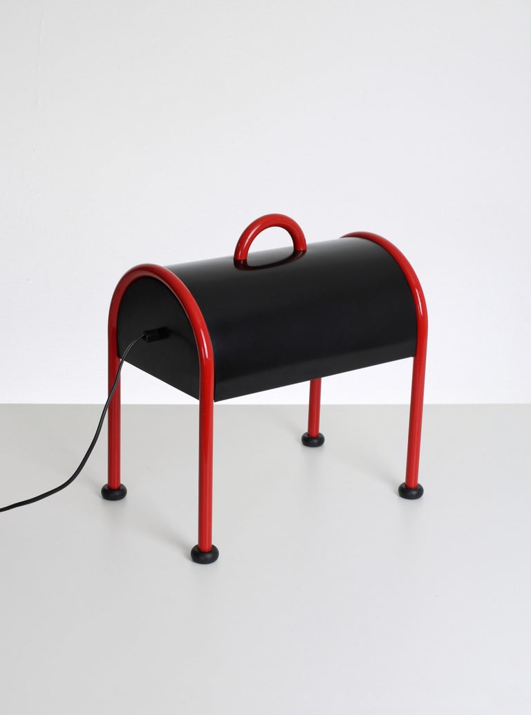 Four-legged table lamp model Valigia. This oddly shaped table lamp is one of the many designs made by Ettore Sottsass. Inspired by the idea of a simple briefcase. The Valigia table lamp is an icon of Italian design, made by Ettore Sottsass for