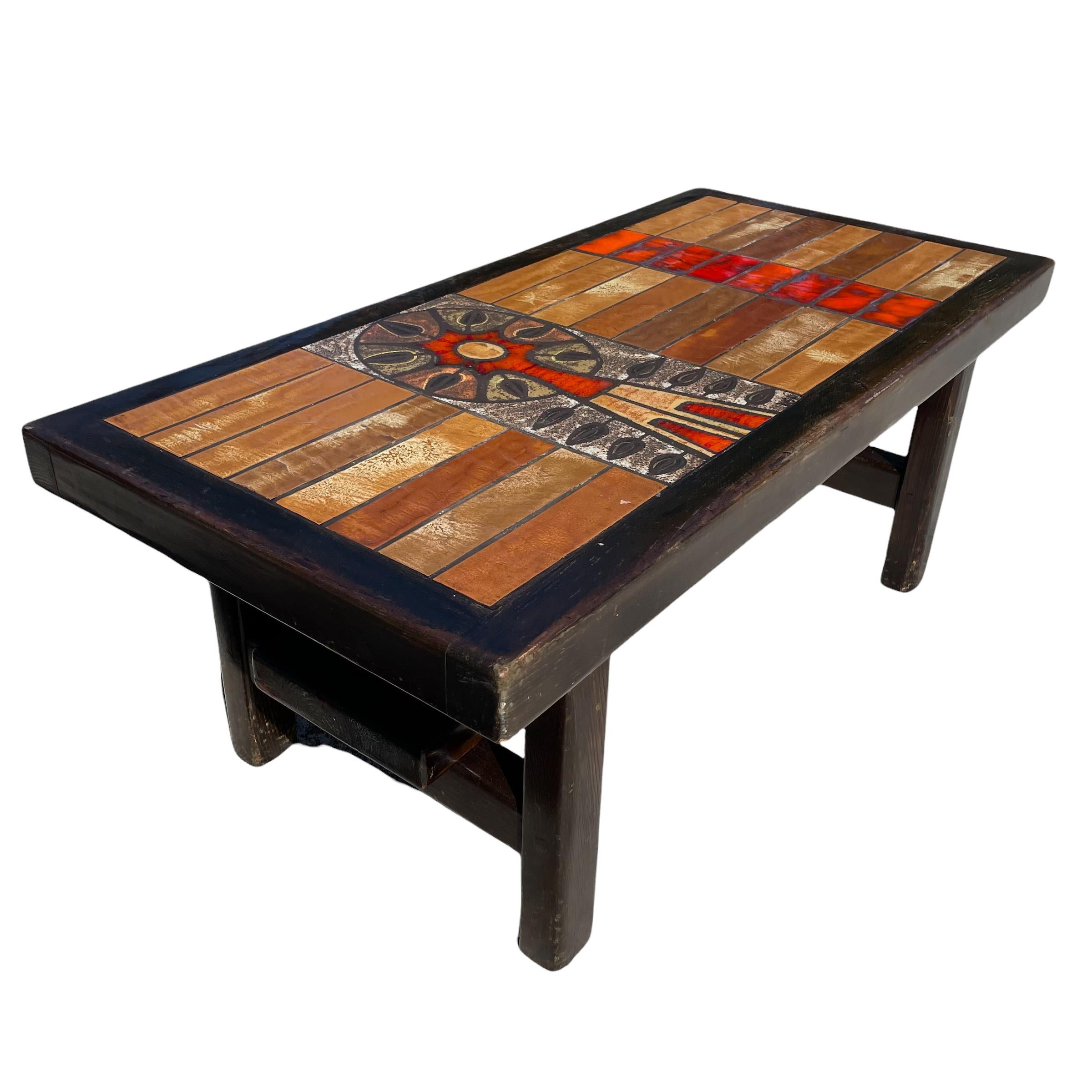 Coffee table in colored ceramic in light brown and red tones with artistic representation reflecting the style of the 1960s, base, contour, and footrest in dark wood.
