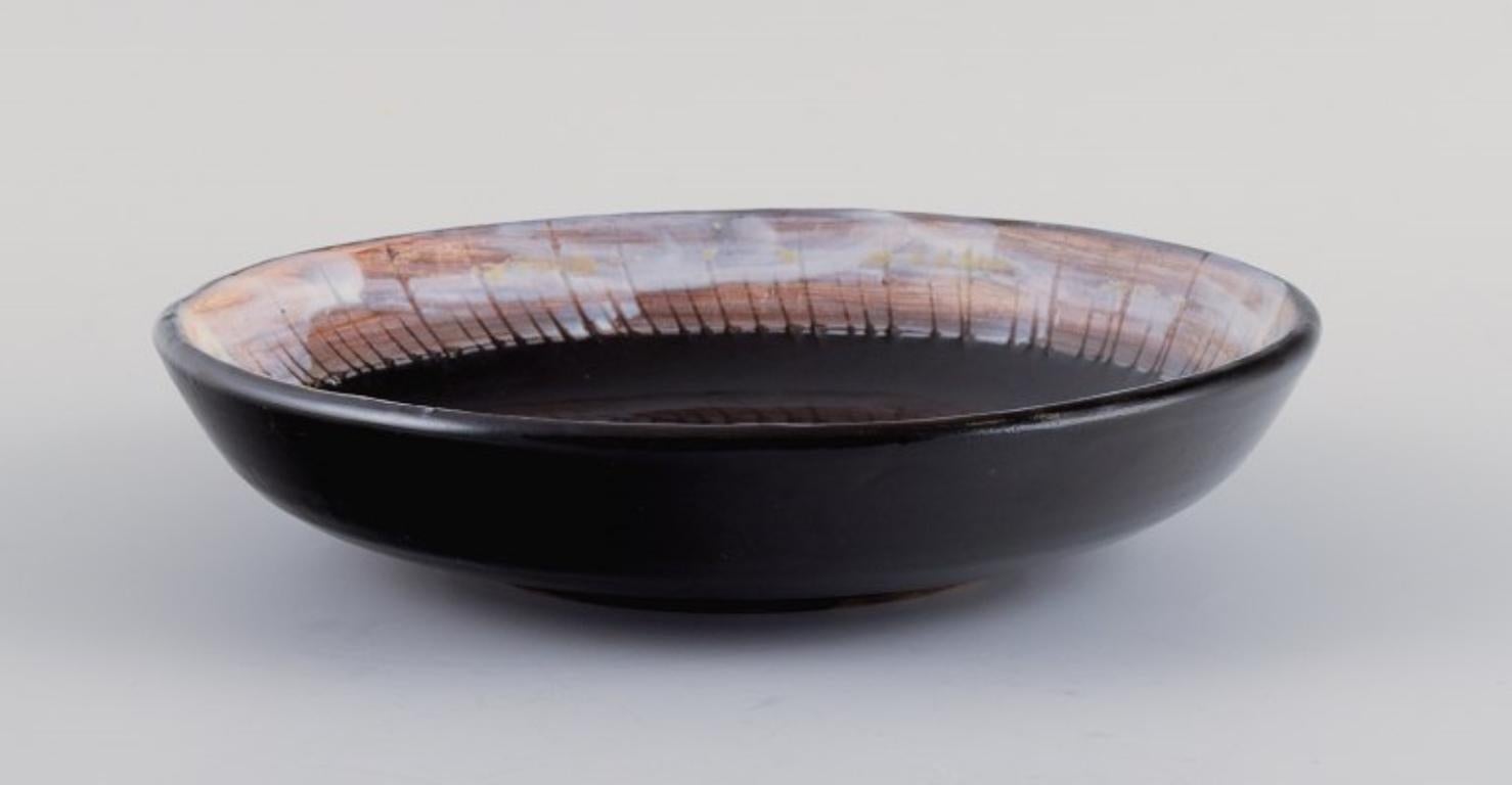 Vallauris, France, unique ceramic bowl in black glaze with a female motif.
Approx. 1970s.
Signed.
In perfect condition.
Dimensions: D 19.5 x H 4.5 cm.