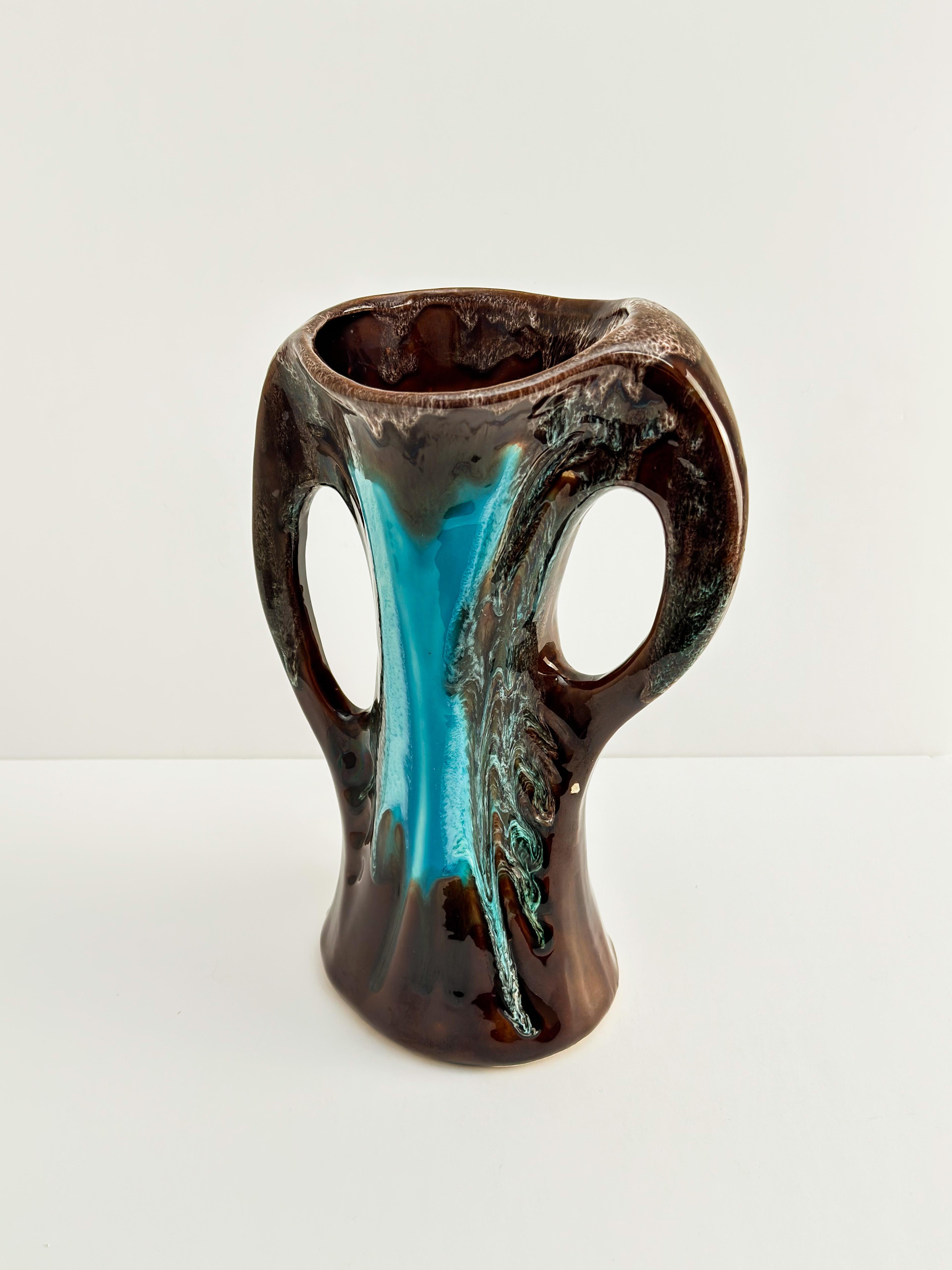 A vintage French ceramic vase by Vallauris, handcrafted around the 1960s in the famed French village.

This sculptural pottery piece, in the form of a vase, features smooth, sweeping curves paired with organically shaped double handles—a distinctive