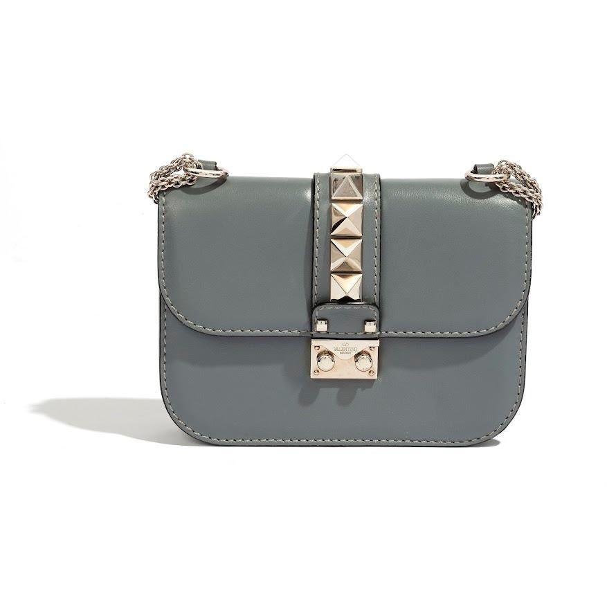 Expertly crafted by Valentino Garavani, this Mini Grey Rockstud Bag boasts ancient architectural-inspired Rockstud embellishments. This mini bag exudes timeless elegance and impeccable attention to detail.

This Mini Rockstud bag in grey is made out
