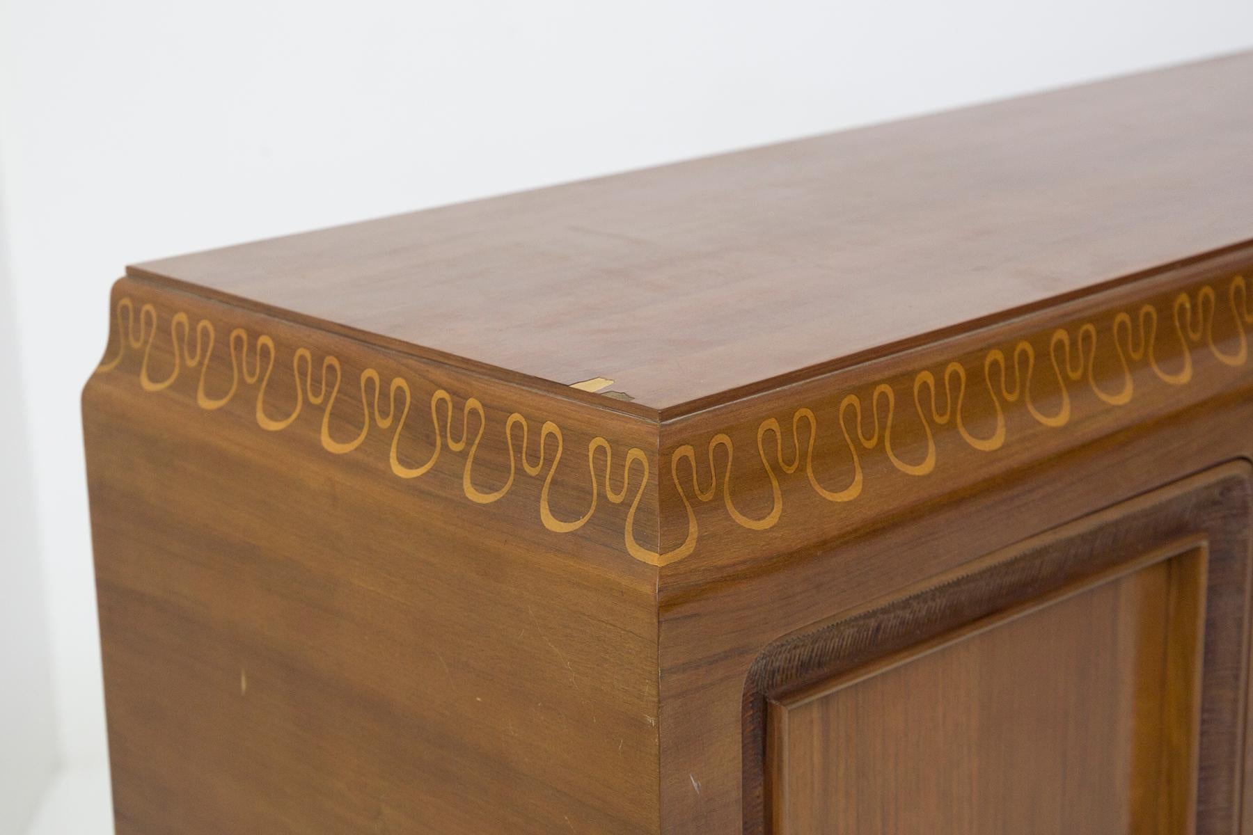 Splendid sideboard designed in the 1950s for the famous Valzania production with original label.
The sideboard is entirely made of solid walnut wood decorated and carved with elegant ornaments and gold-coloured decorations.
There are 4 legs