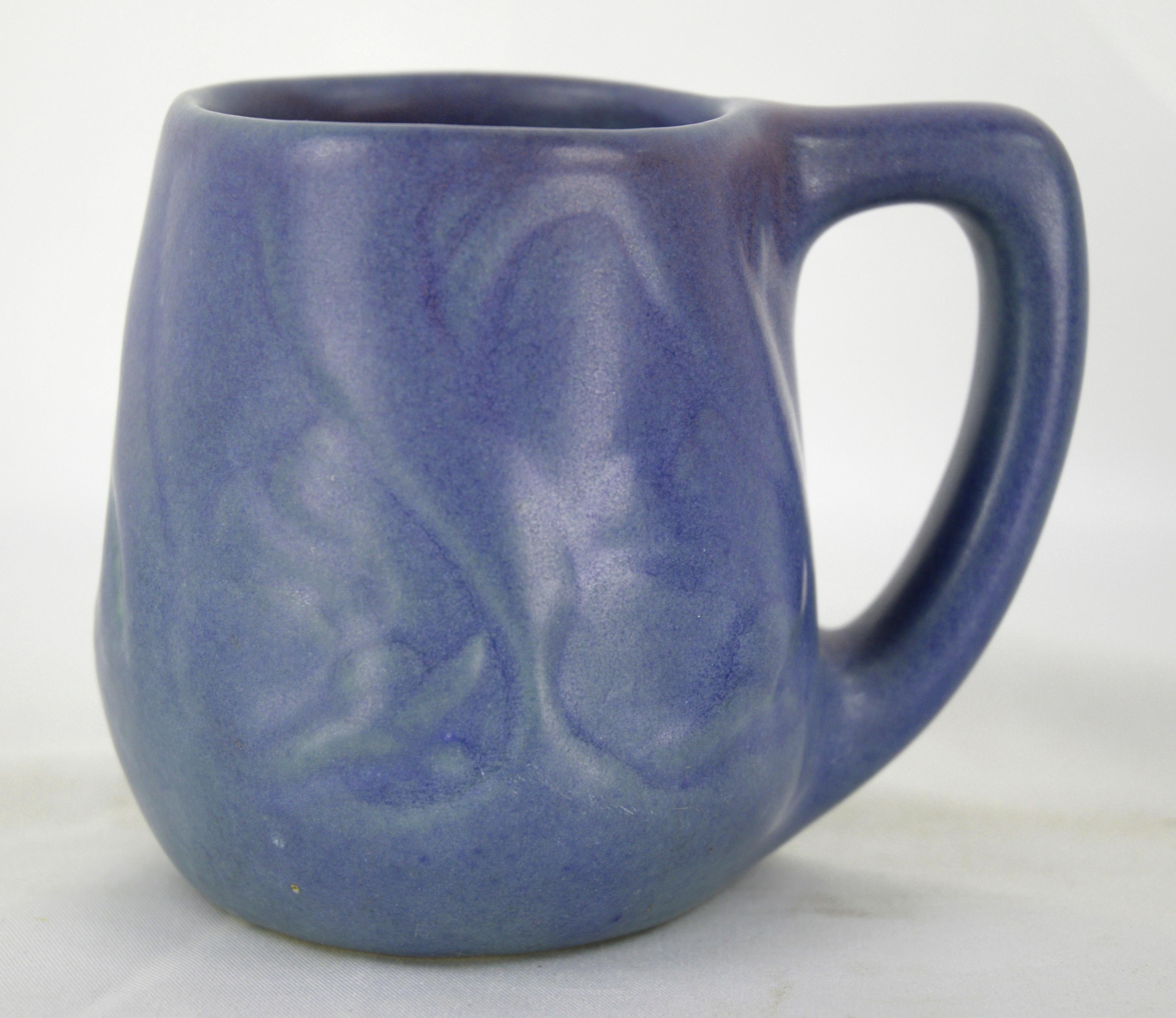Elegant blue-purple mug by Van Briggle Pottery. This color is uncommon - most of these pieces were made in a turquoise color. Finished by Clara Beyers (1989-1997). Glazed by either Annette Moody or Garoid (Gary) Dhondt.

Maker's logo, name, and