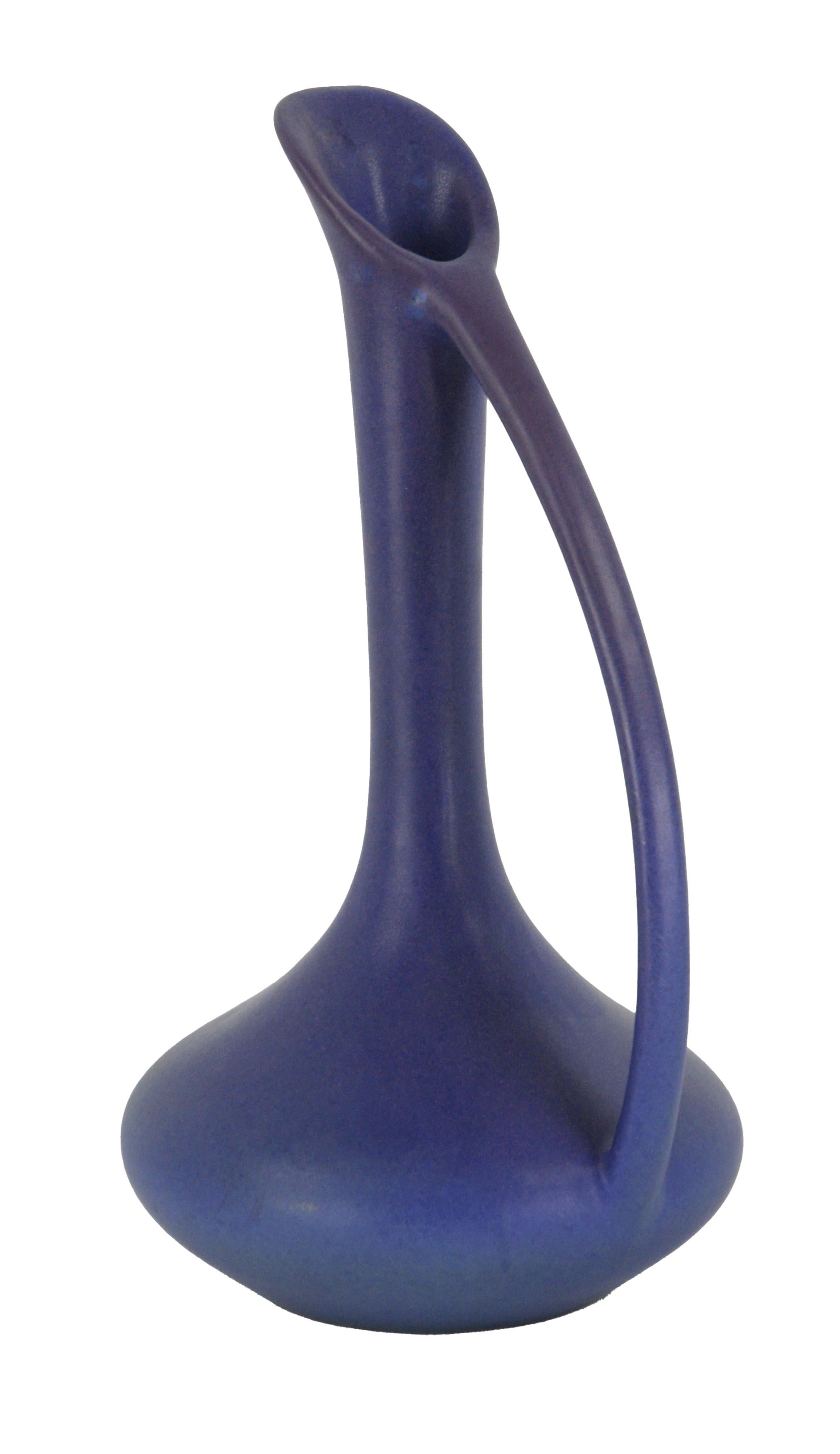 Elegant blue-purple water pitcher by Van Briggle Pottery. This color is uncommon - most of these pieces were made in a turquoise color. Finished by Carolyn French. Glazed by either Annette Moody or Garoid (Gary) Dhondt.

Maker's logo, name, and