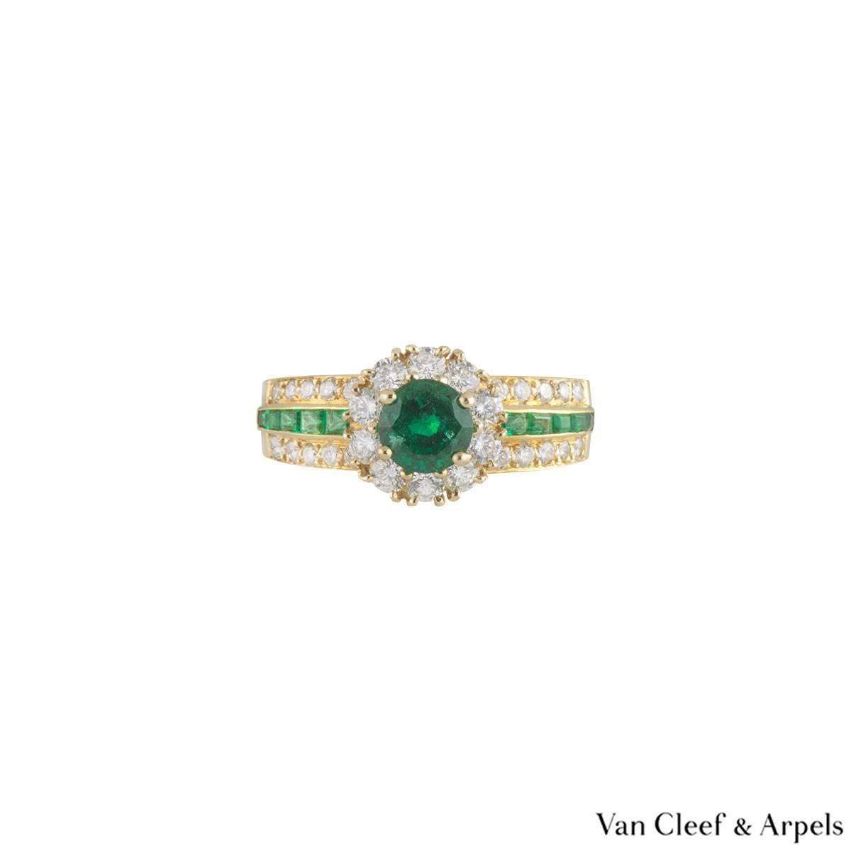 A beautiful 18k yellow gold Van Cleef & Arpels emerald and diamond ring. The ring comprises of a round brilliant cut emerald set to the centre with a halo of round brilliant cut diamonds. The centre is complemented with baguette cut emeralds on the