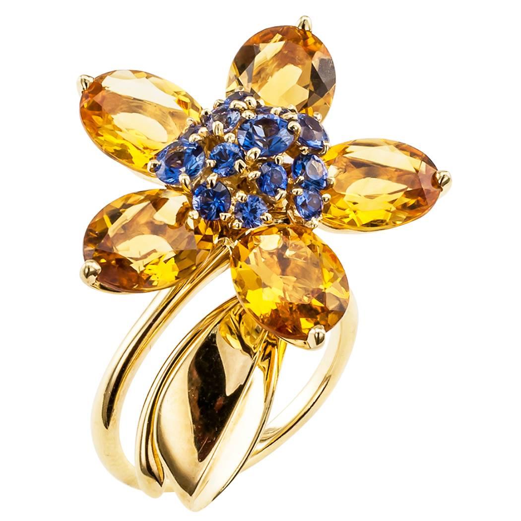 Van Cleef & Arpels Hawaii ring set with citrines and sapphires in yellow gold. The single flower design has a gentle oscillating motion, enlivened by brilliant citrine petals and pistils set with round blue sapphires, topping a leaf motif to the