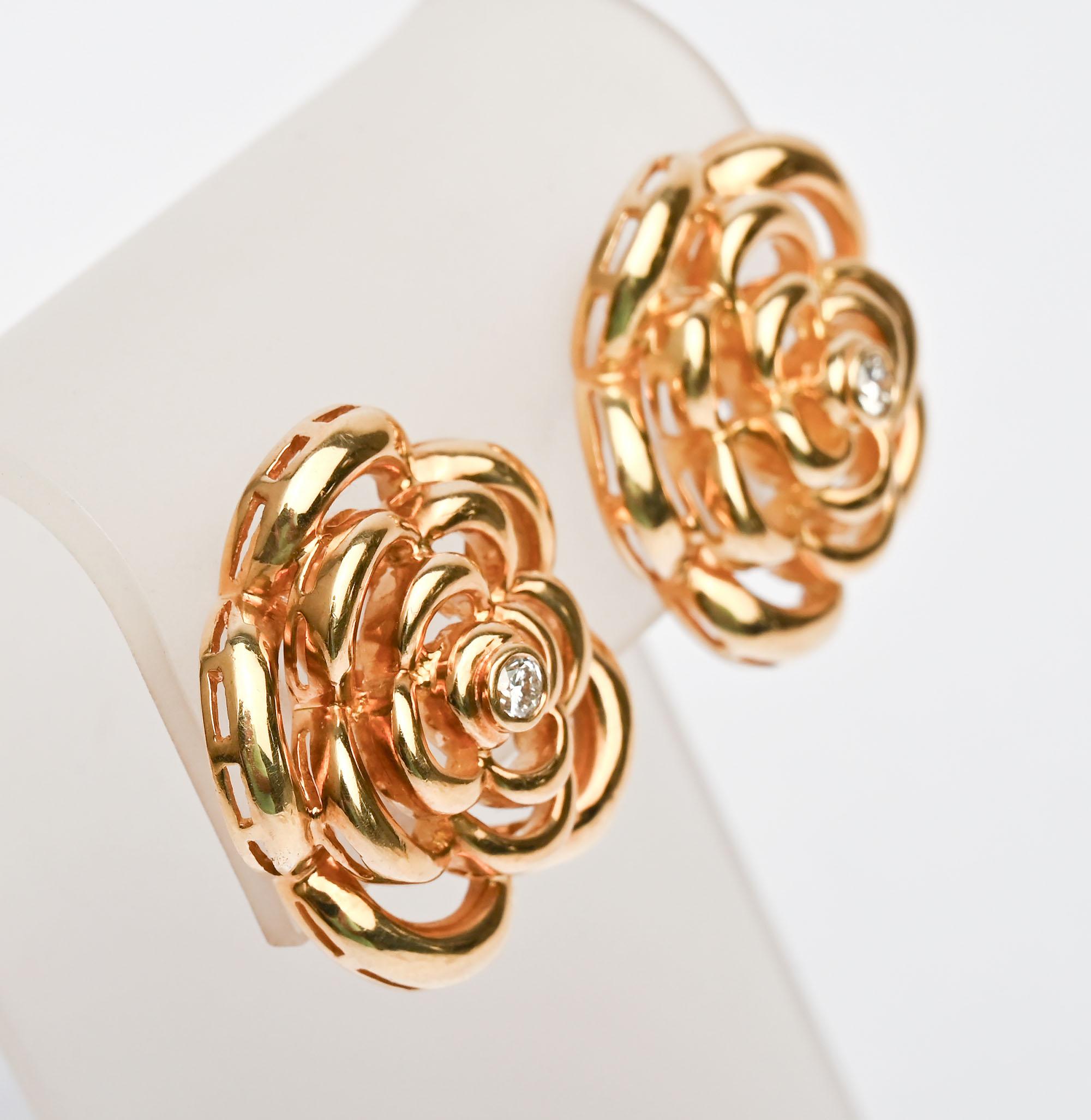 Magnifiques boucles d'oreilles en forme de fleurs de Van Cleef and Arpels de la collection Camillia. Les fleurs stylisées présentent trois rangées de demi-cercles ouverts ponctués d'un centre en forme de diamant. Les boucles d'oreilles sont dotées