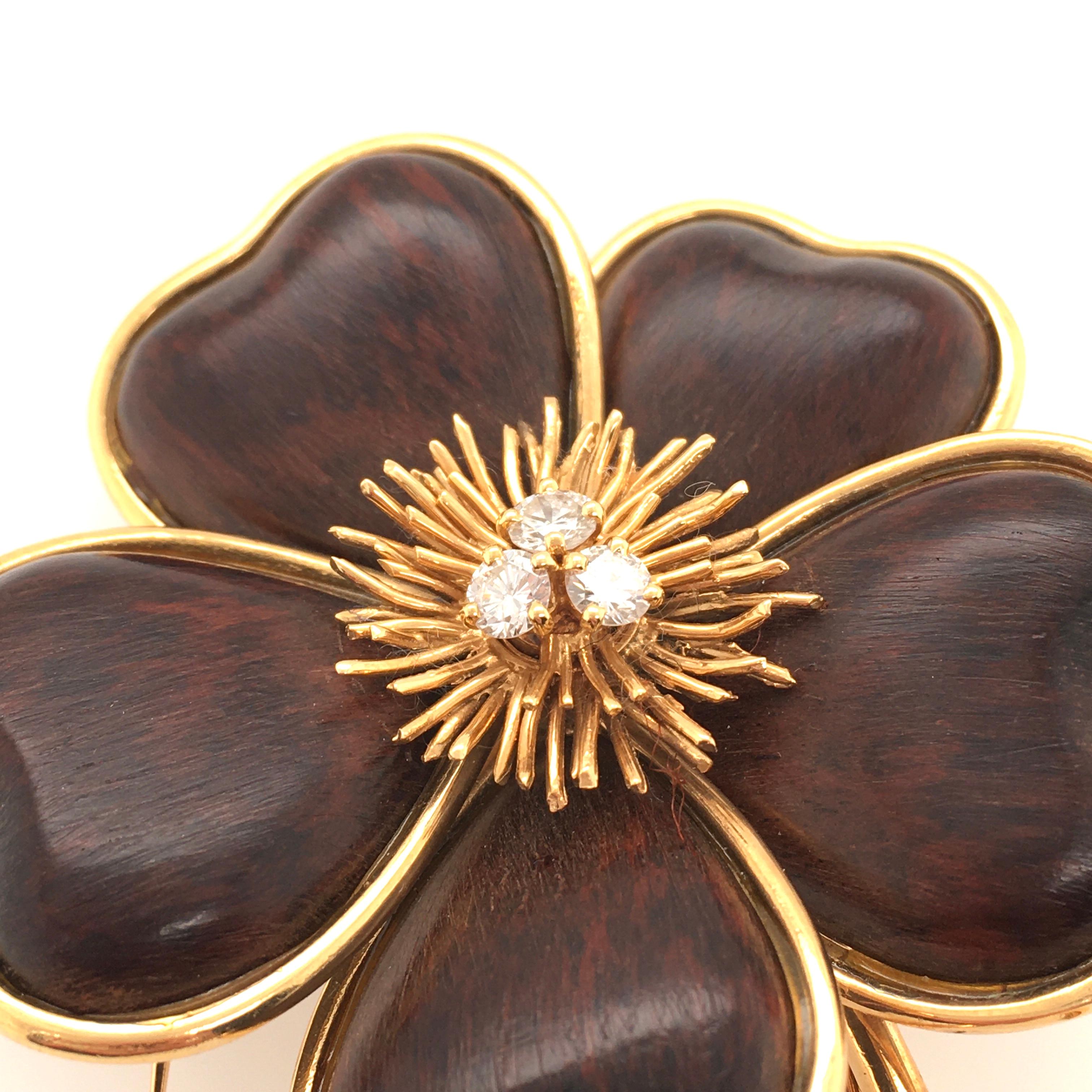 An 18 karat yellow gold, wood and diamond Nerval brooch. Van Cleef & Arpels. Designed as a sculpted 18k gold flower with wooden petals, extending polished gold stem and textured leaf,  centering a gold spray, enhanced by three (3) circular cut
