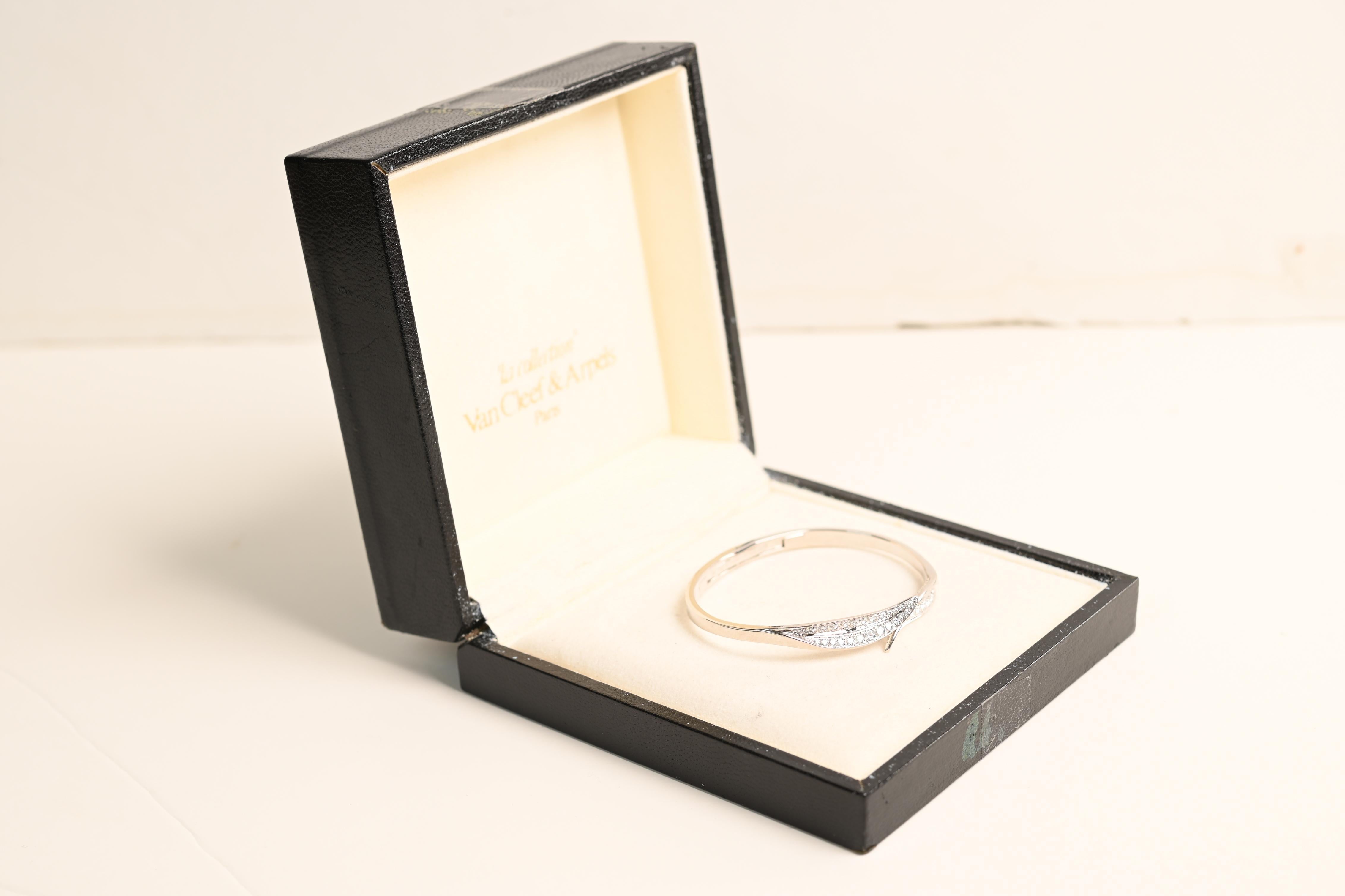 This exquisite Van Cleef & Arpels bangle bracelet is a masterpiece of elegance and craftsmanship. Showcasing a striking design, the bracelet features two intricately crafted leaf motifs, each adorned with pave-set, round brilliant-cut diamonds. The