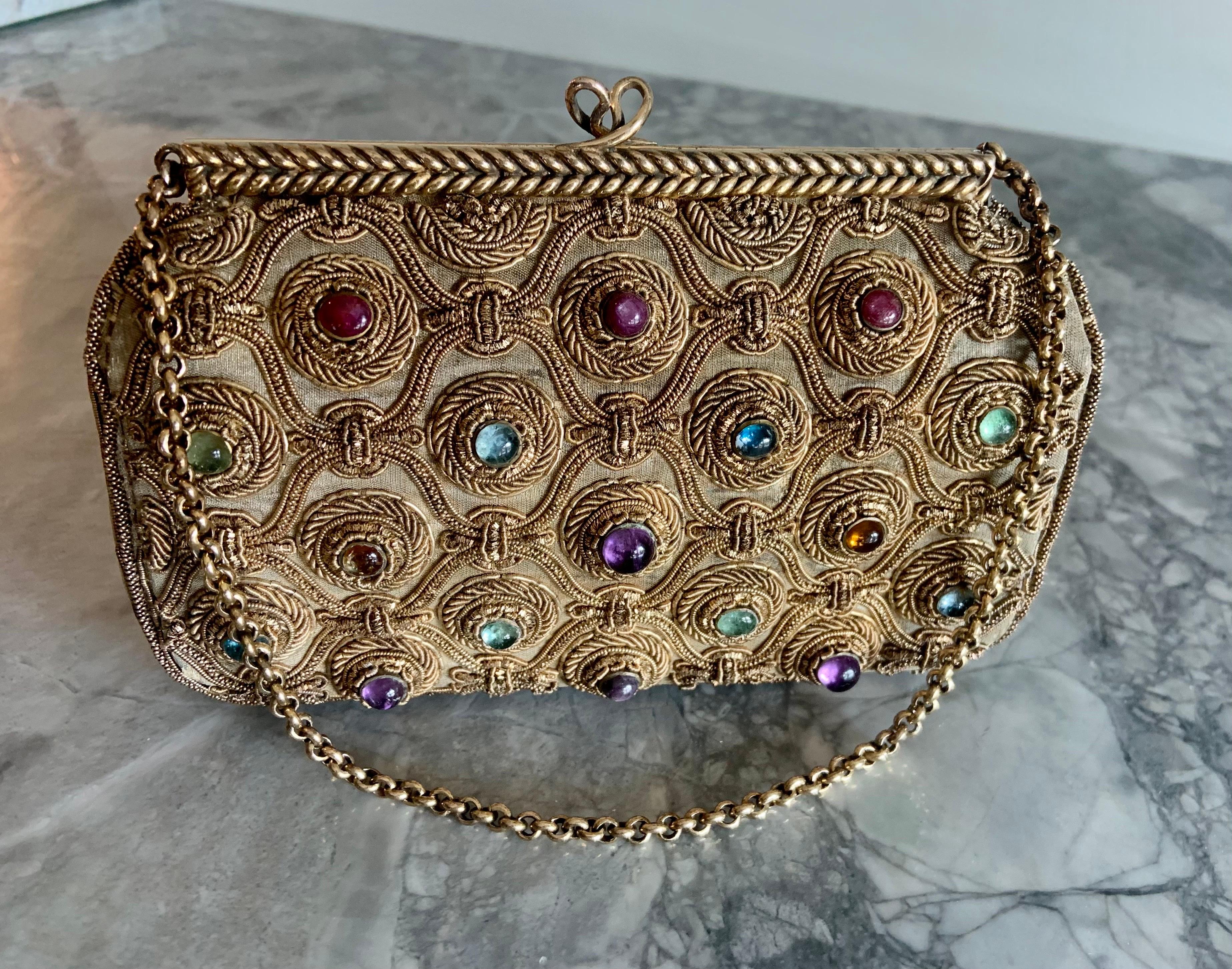 A rare and collectible piece from Van Cleef & Arpels, this mid century gem set evening bag was Made in France.  It has a large carved amethyst below the clasp on the front of the bag. This is surrounded by cabochon rubies, emeralds, amethysts,