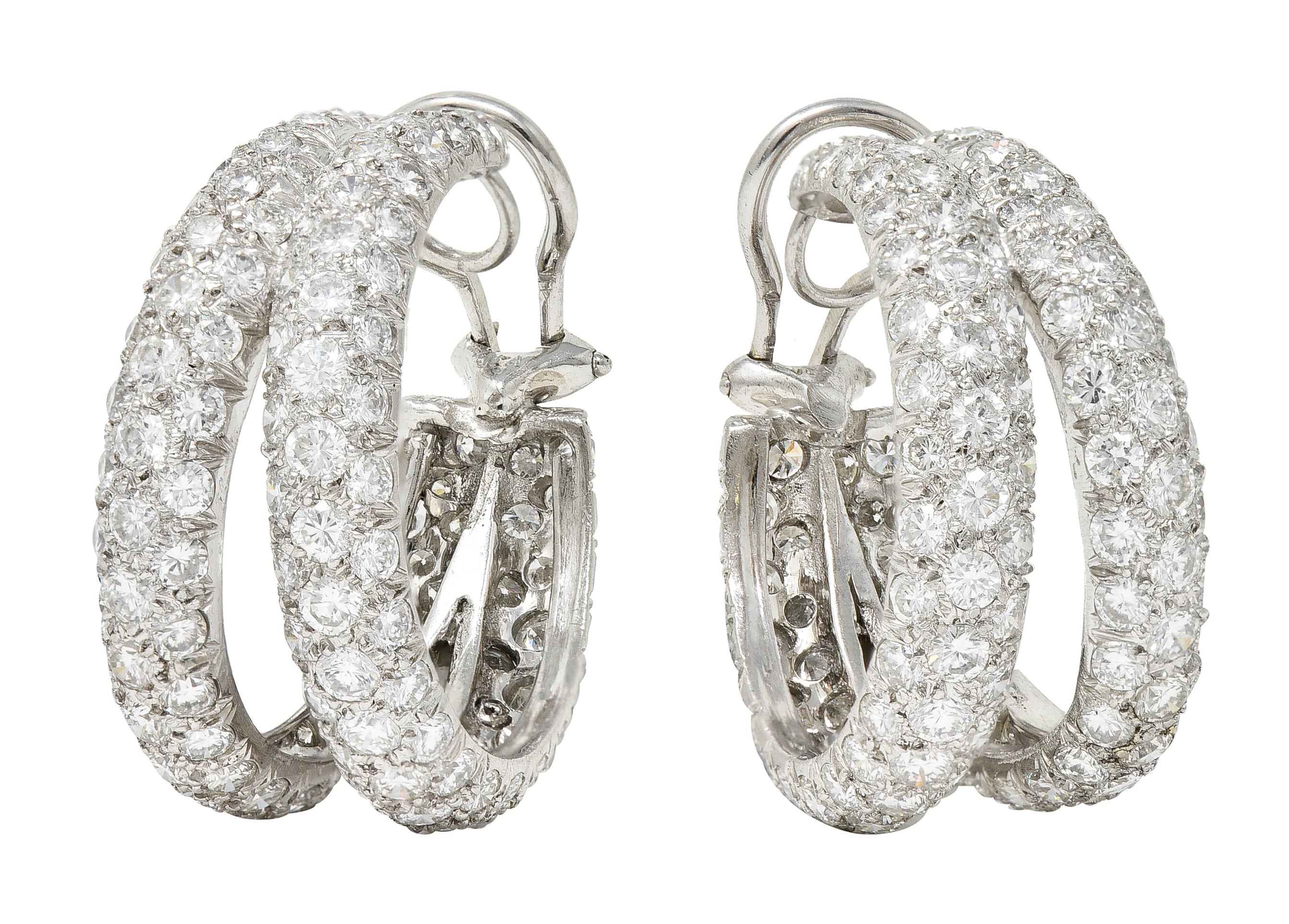 Ear-clip earrings are designed as substantial hoops in a split motif. Pavè set throughout by round brilliant cut diamonds. Weighing in total approximately 13.00 carats - F/G color with VS clarity. Completed by hinged omega backs. Inscribed PLAT for