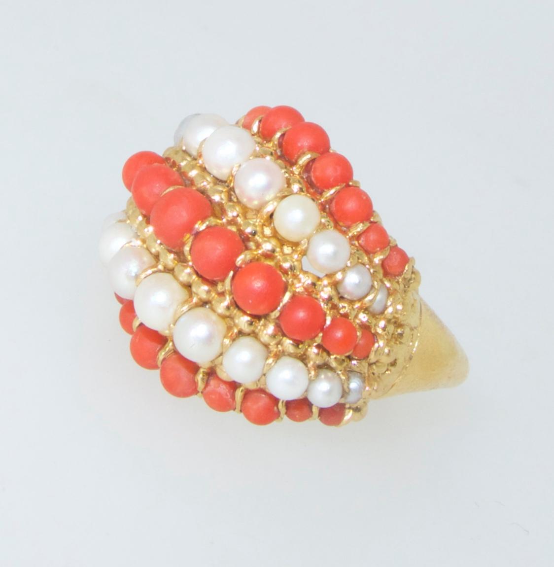 Van Cleef & Arpels circa 1960 ring possessing fine deep orange natural coral and white round fine pearls.  Done in a swirl like design is classic Van Cleef & Arpels work during this decade.  This 18K yellow gold ring is in fine condition and signed,