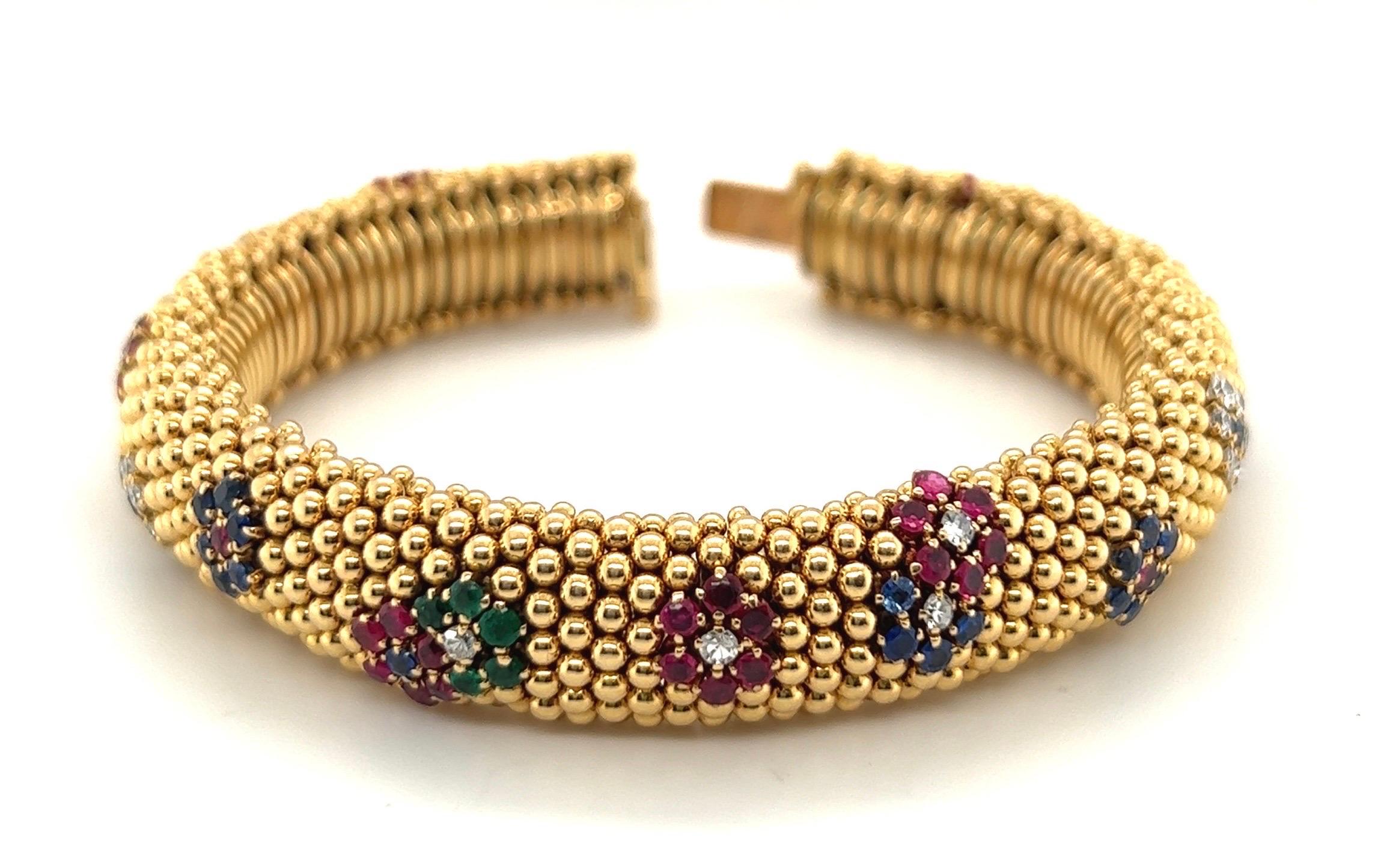 Gorgeous Van Cleef & Arpels 18 karat yellow gold, diamond, sapphire and emerald Bagatelle bracelet, circa 1960.
Designed as a highly flexible bombé bracelet composed of a beaded ground decorated with applied ruby, sapphire, emerald and diamond