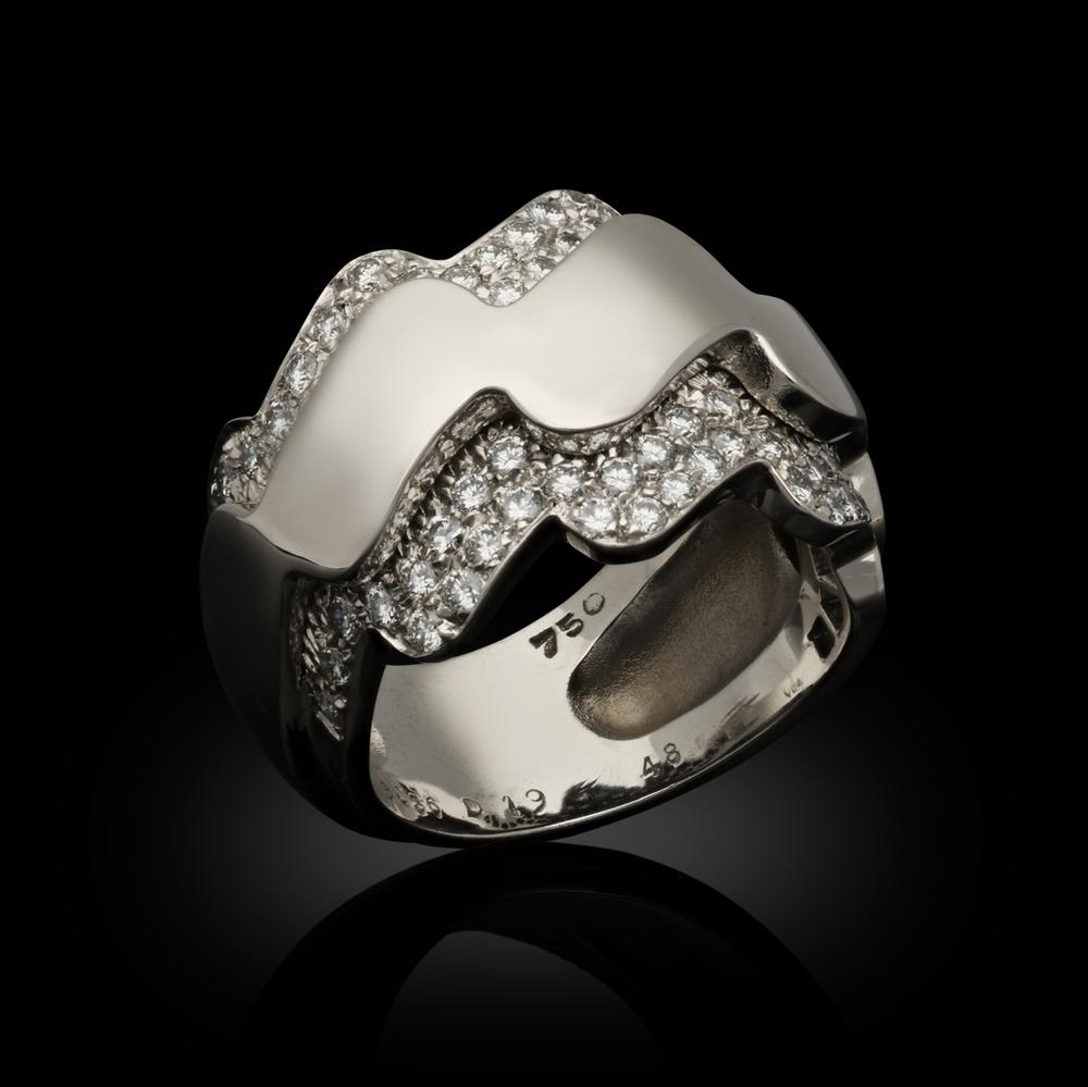 An 18ct white gold and diamond dress ring by Van Cleef & Arpels c.2000s, the ring of undulating wave like form in white gold, tapering towards the back, the central raised band of highly polished gold edged to each side with a double row frame of
