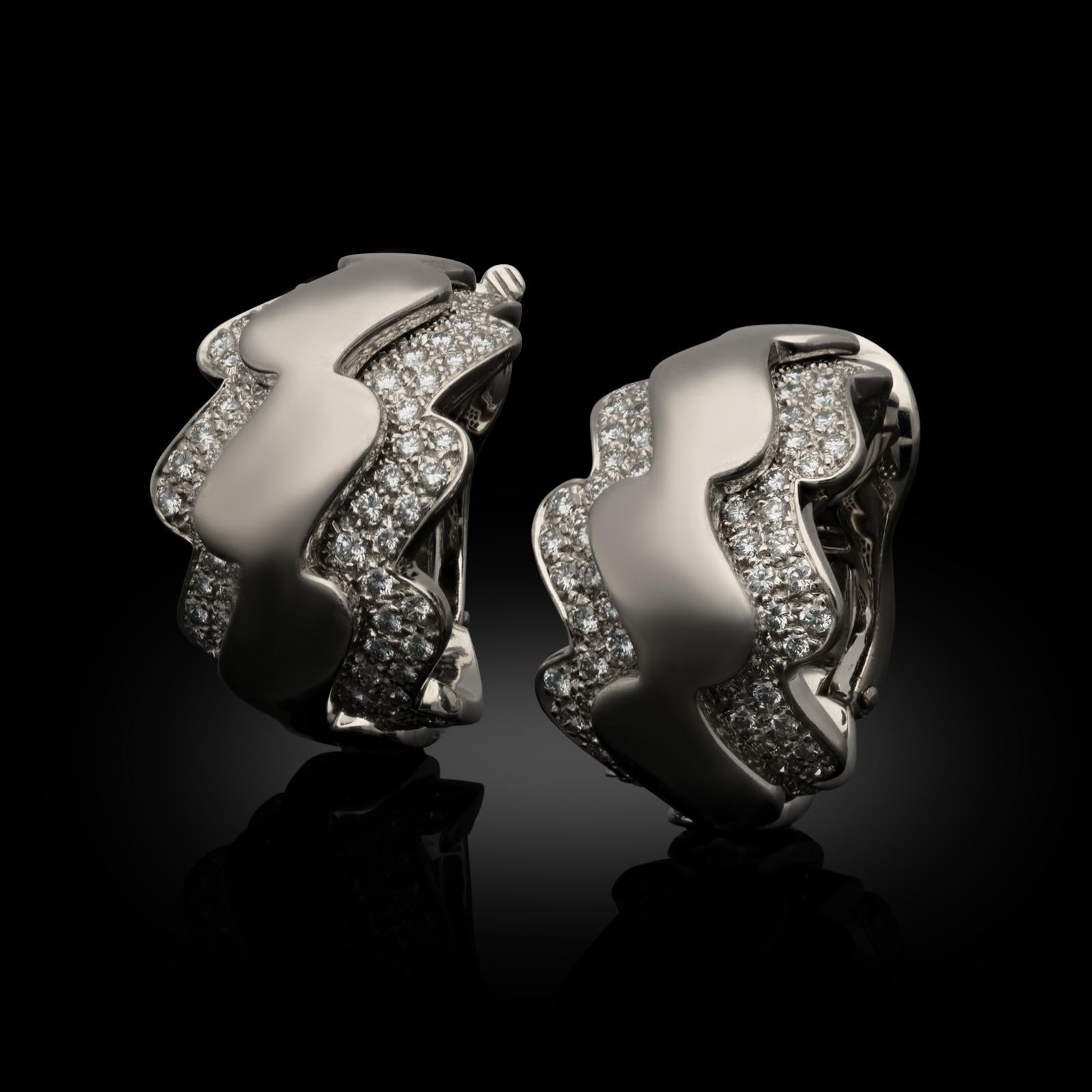 A pair of 18ct white gold and diamond earrings by Van Cleef & Arpels c.2000s, the hoop shape earrings of undulating wave like form in white gold have a central raised band of highly polished gold edged to each side with a double row frame of round