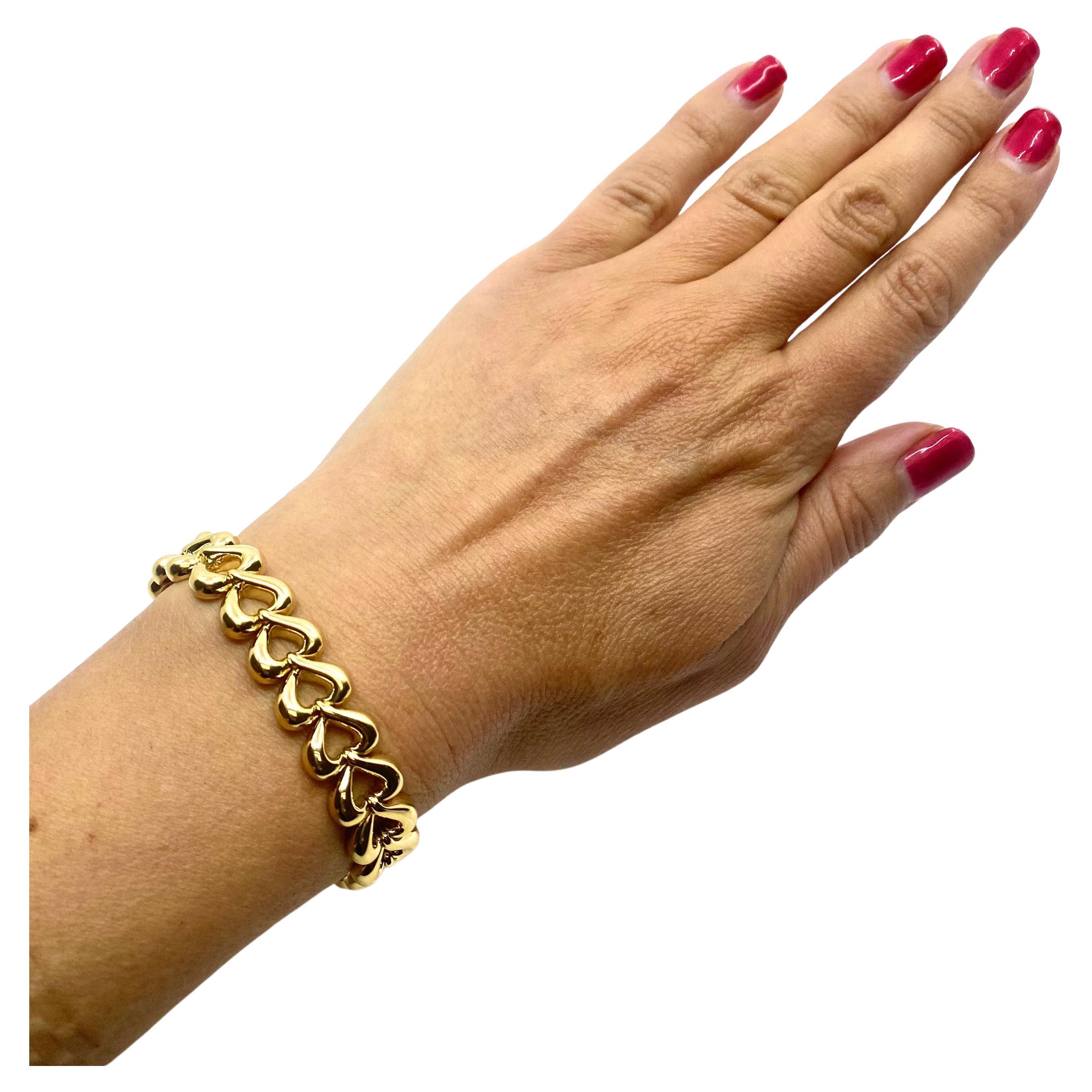 A glossy Van Cleef & Arpels 18k gold bracelet crafted of heart-shaped links. It’s a minimal yet chic piece that speaks volumes about feelings. The links are open work, and there is a cute little solid heart topping the clasp. This VCA gold bracelet
