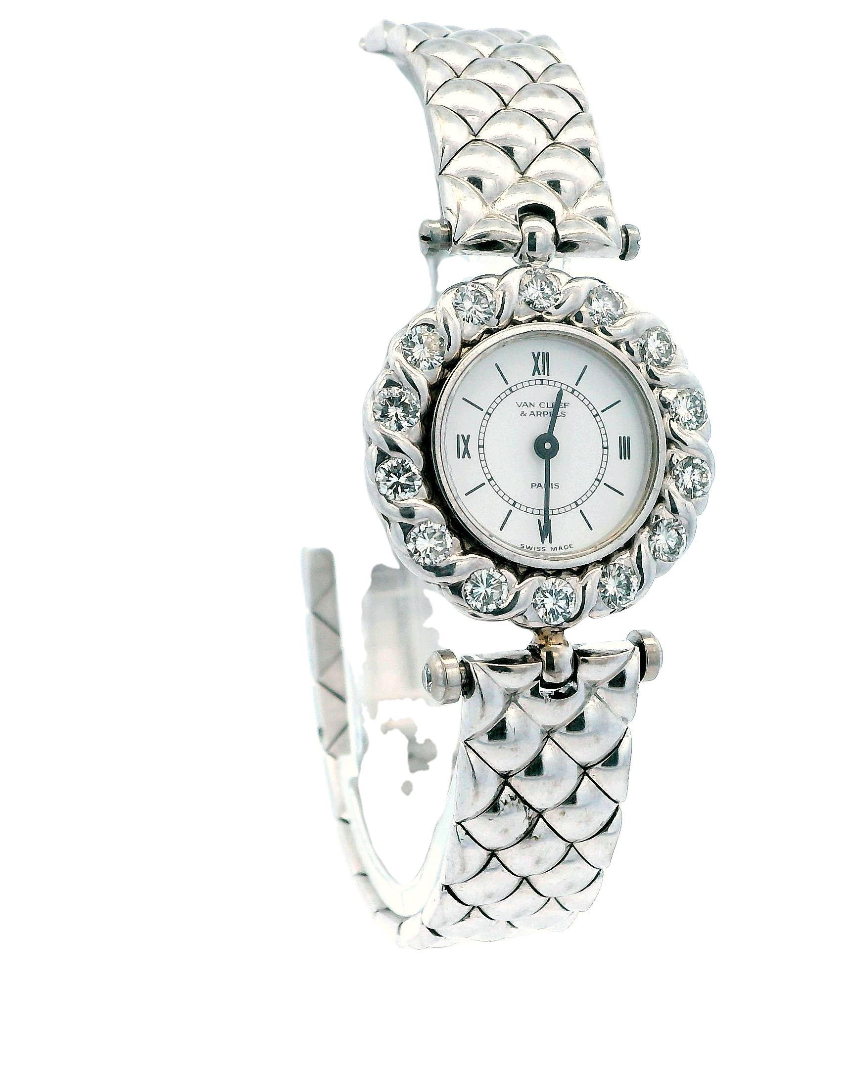 A Van Cleef & Arpels watch in 18k gold, featuring a round shape with a white dial and stick indexes. The bezel is adorned with diamonds. The case is silver in color, crafted from 18k gold, and has a screwback design. The band, also in silver, is