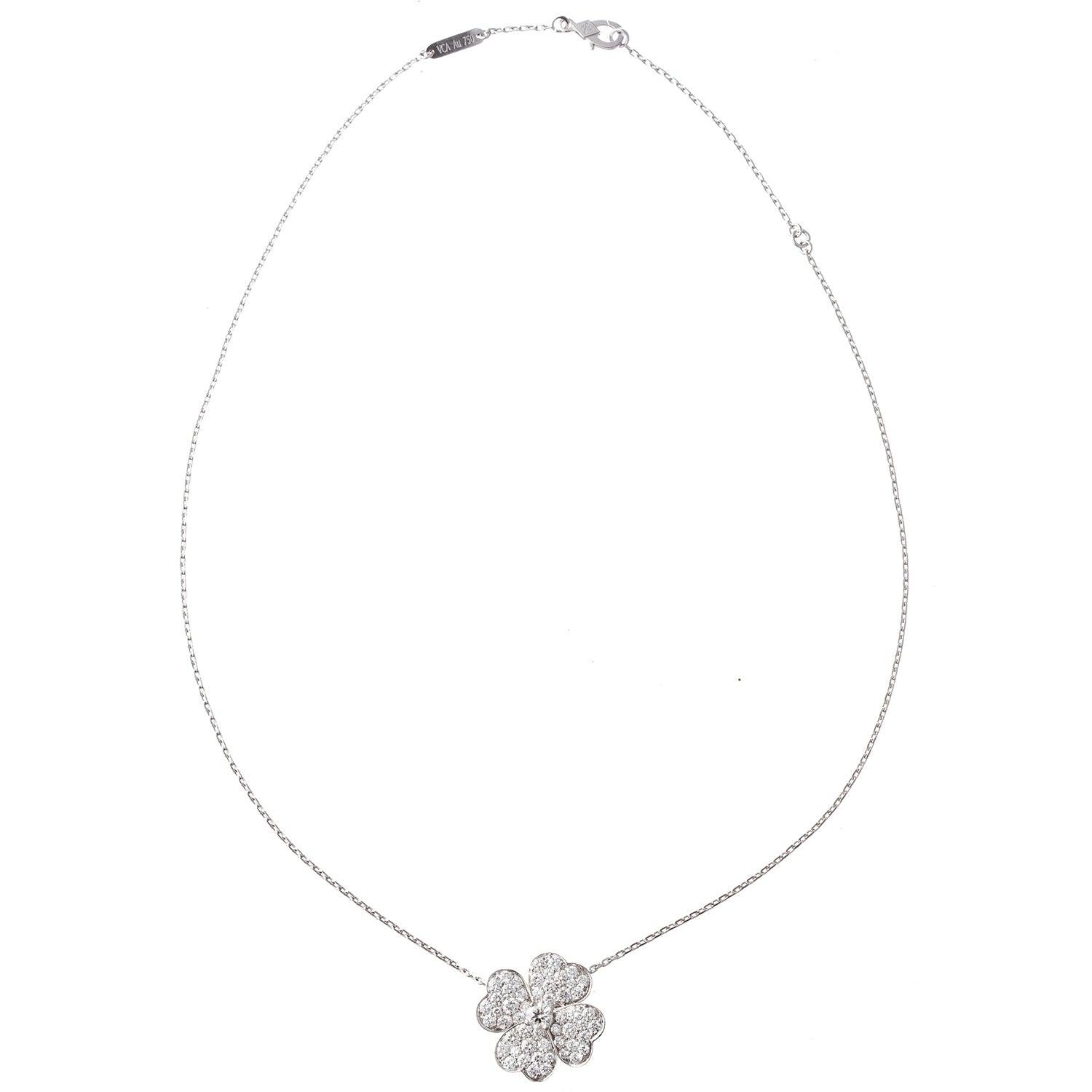 Pendente/spilla a clip Van Cleef & Arpels Cosmos in oro bianco 18 carati, con un diamante rotondo taglio brillante centrale circondato da quattro petali con pavé di diamanti rotondi taglio brillante più piccoli. Pendente/spilla sospeso sulla collana