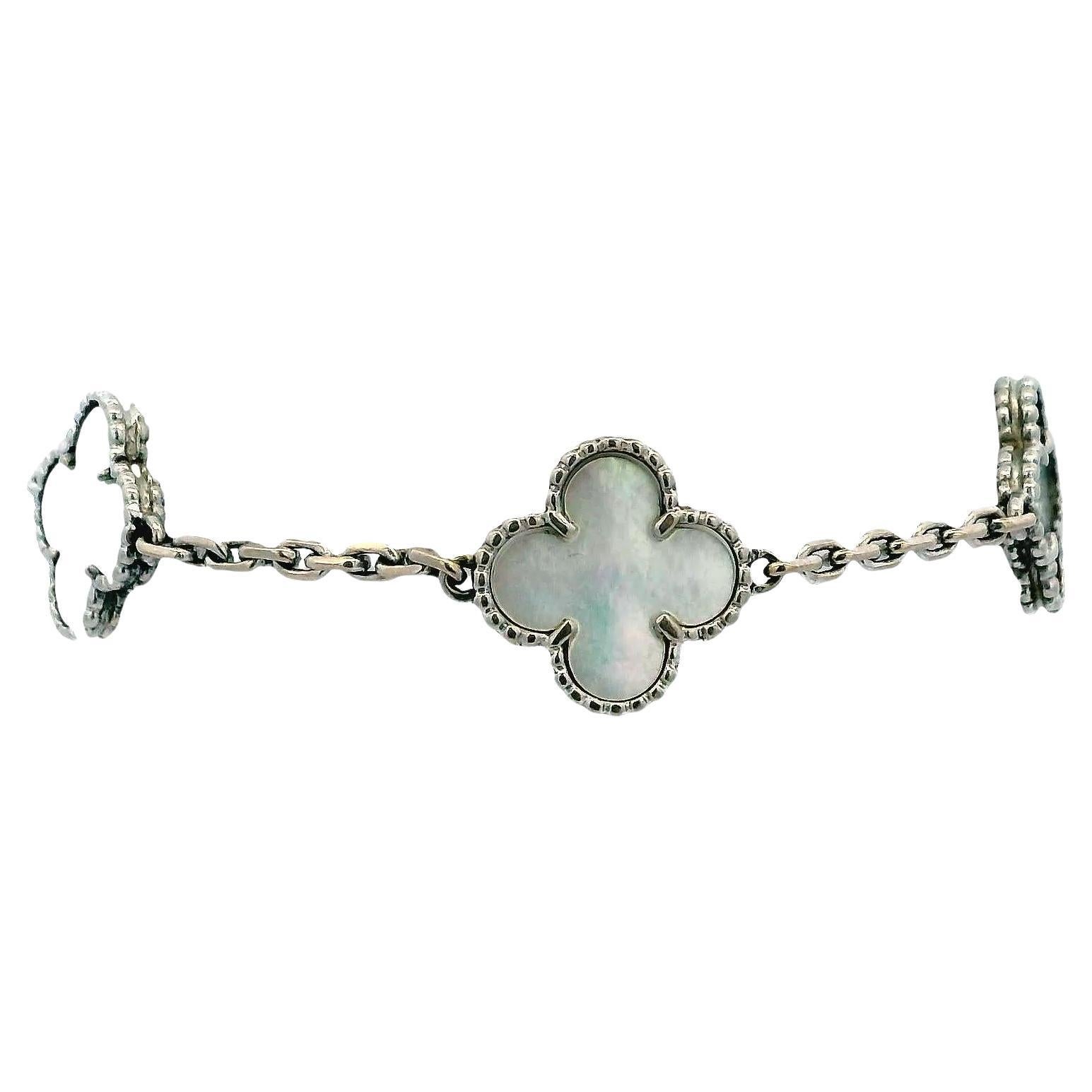 Questo squisito bracciale di Van Cleef & Arpels presenta una serie di motivi a forma di trifoglio, ciascuno realizzato in madreperla lucida e incorniciato da delicati bordi di perline. I motivi sono collegati tra loro da una raffinata catena in oro