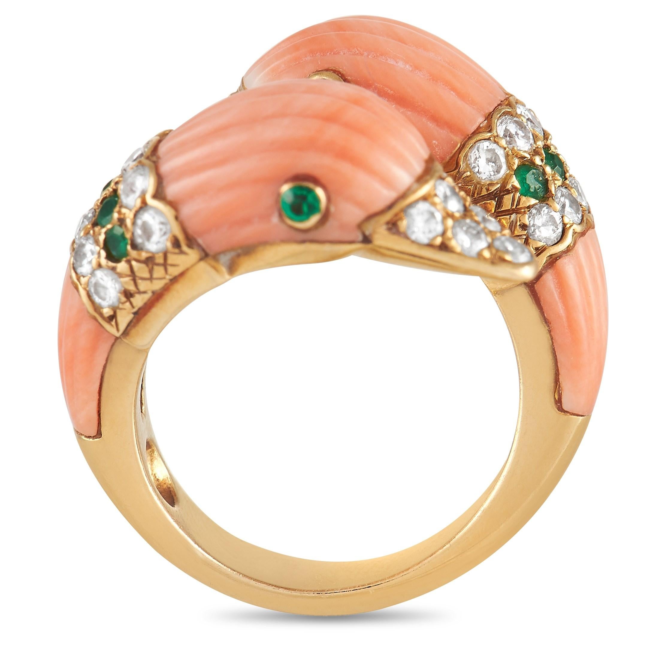 This statement-making ring's design combines whimsy and elegance in equal measure. It features a sculpted yellow gold open shank with two ends shaped like duck heads. Each duck head bears a fluted angel skin coral with emerald eyes and a