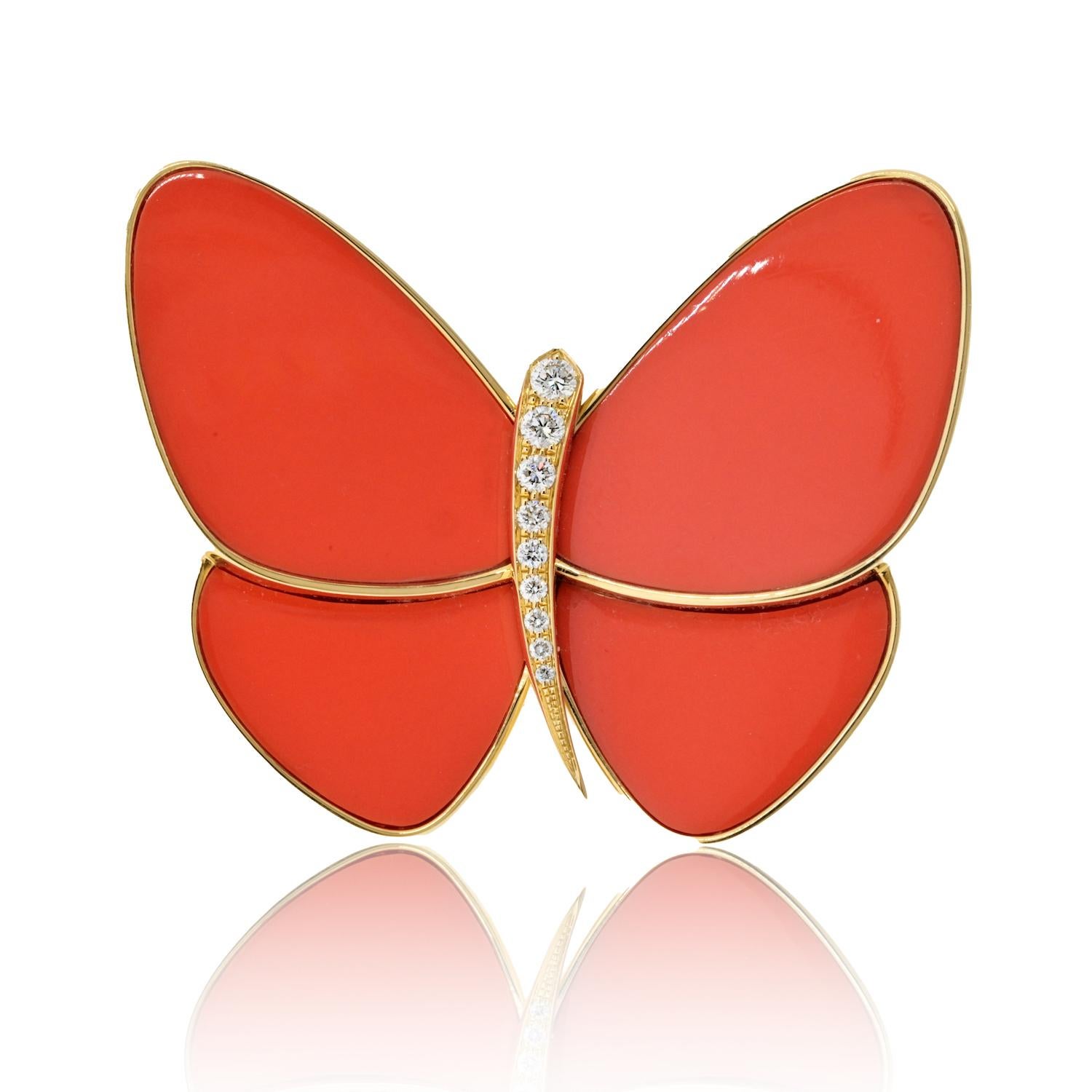 Van Cleef & Arpels presents a mesmerizing creation: a stylized butterfly adorned with exquisite coral inlaid wings. The wings, a rich opaque medium reddish-orange hue, captivate the eye with their vibrant color. At the heart of this enchanting